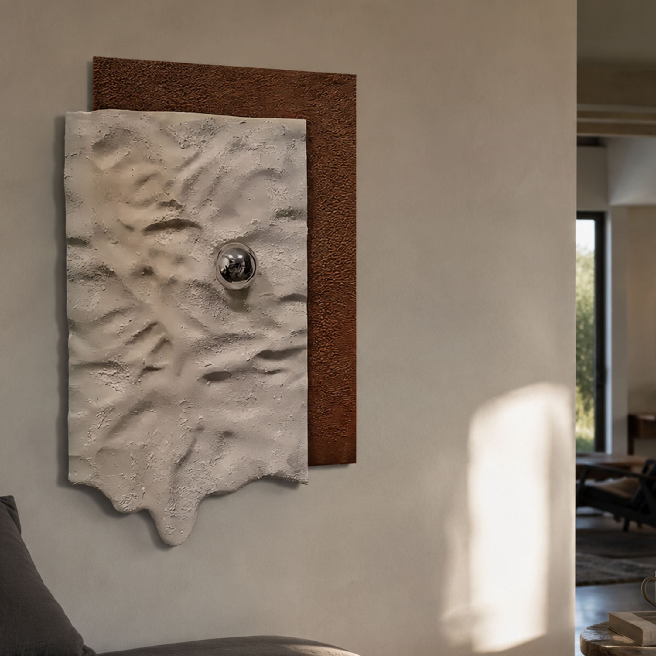 Calidora Terra Sculpted Textured 3D Relief Wall Art with a brown base, draped white sheet, and silver sphere, mounted on a neutral wall in a modern living space.