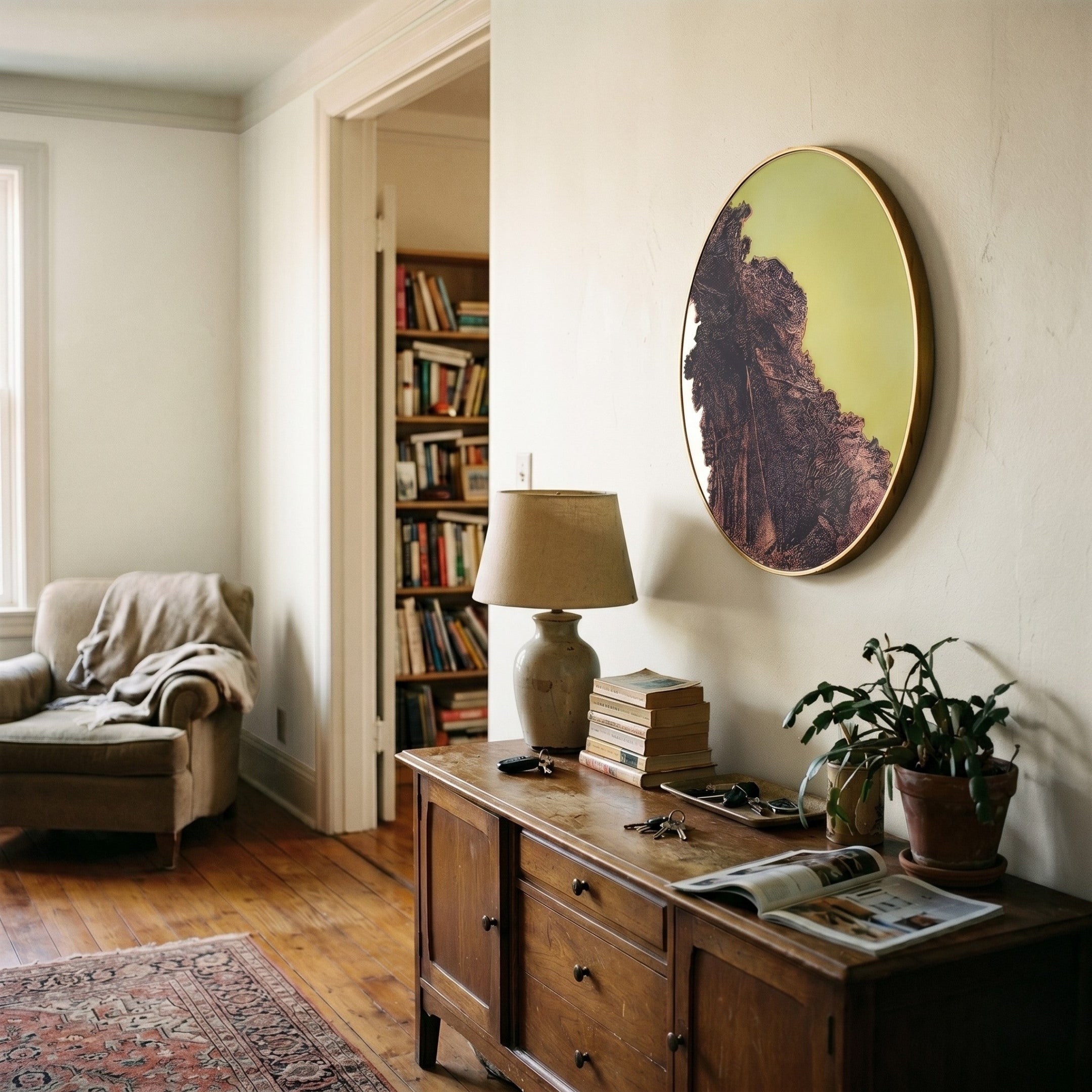Auralune Verdant Rise Textured Abstract Round 3D Wall Art by Giant Sculptures hung above a wooden sideboard in a living room with an armchair and bookshelf nearby.