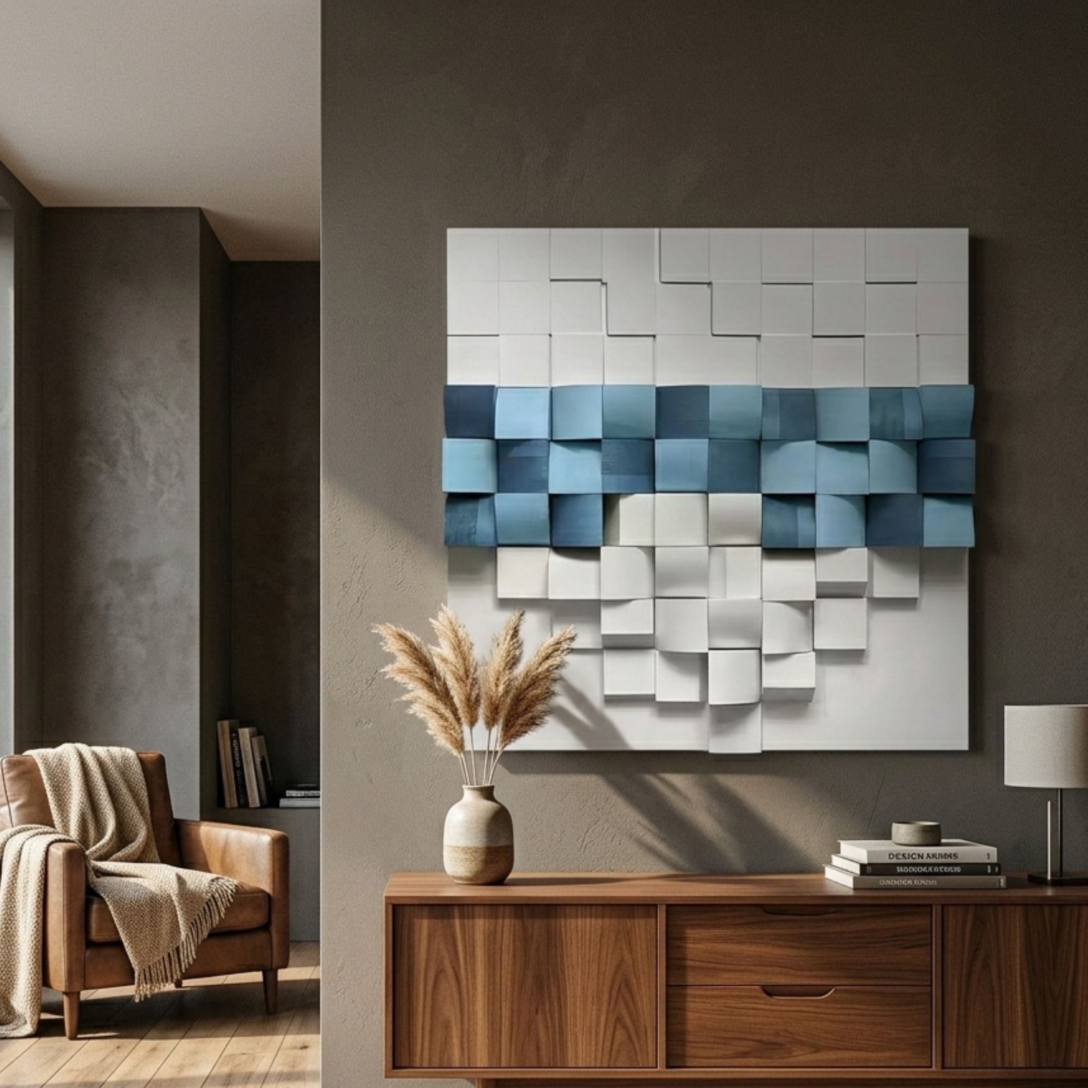 Structura Azure Blue & White 3D Wooden Square Wall Art by Giant Sculptures mounted on a dark wall above a walnut sideboard with pampas grass and a leather armchair.