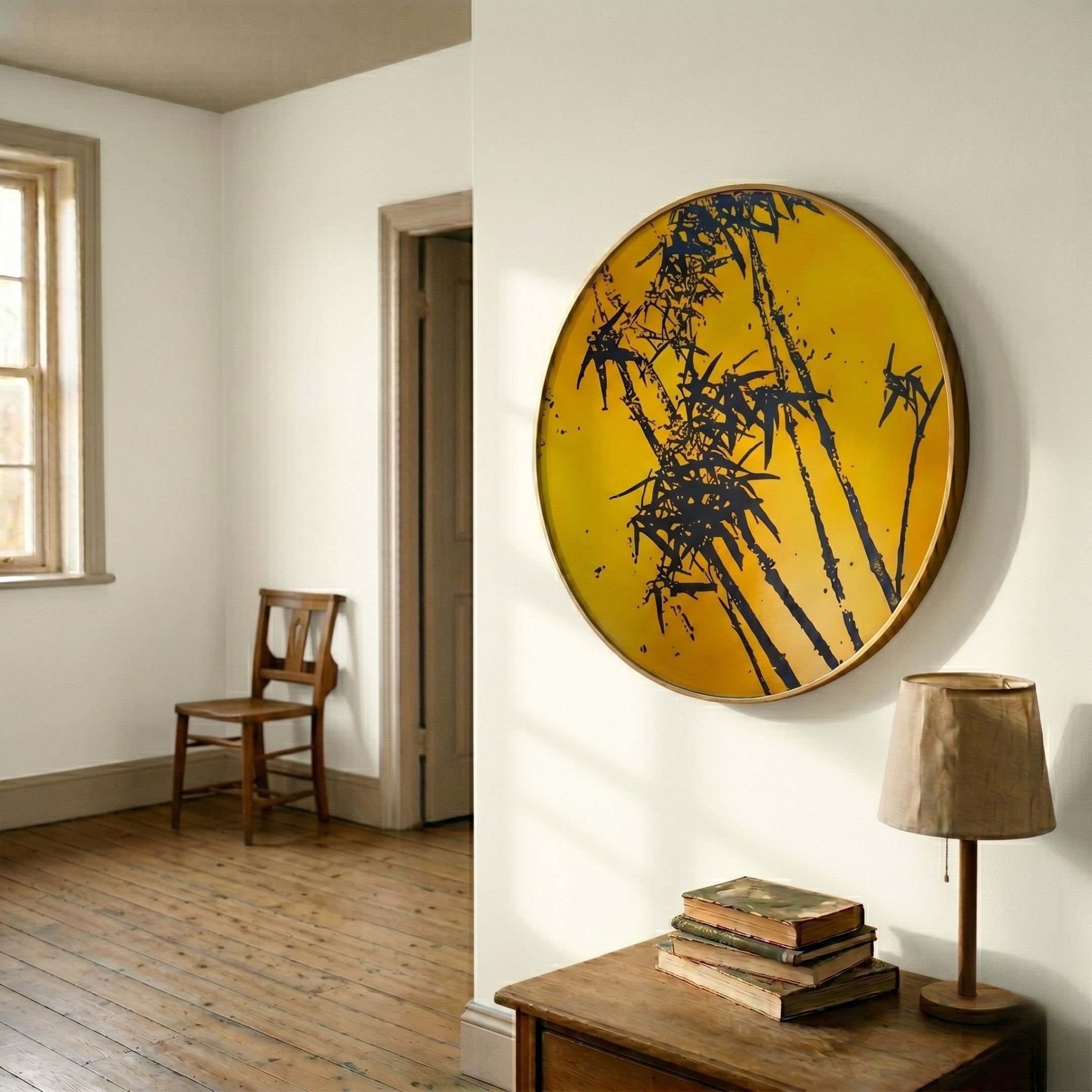A minimalist room with wooden floors, a chair by the window, and a side table with books and a lamp. The white wall features the Auralune Golden Bamboo Silhouette Round 3D Wall Art by Giant Sculptures.
