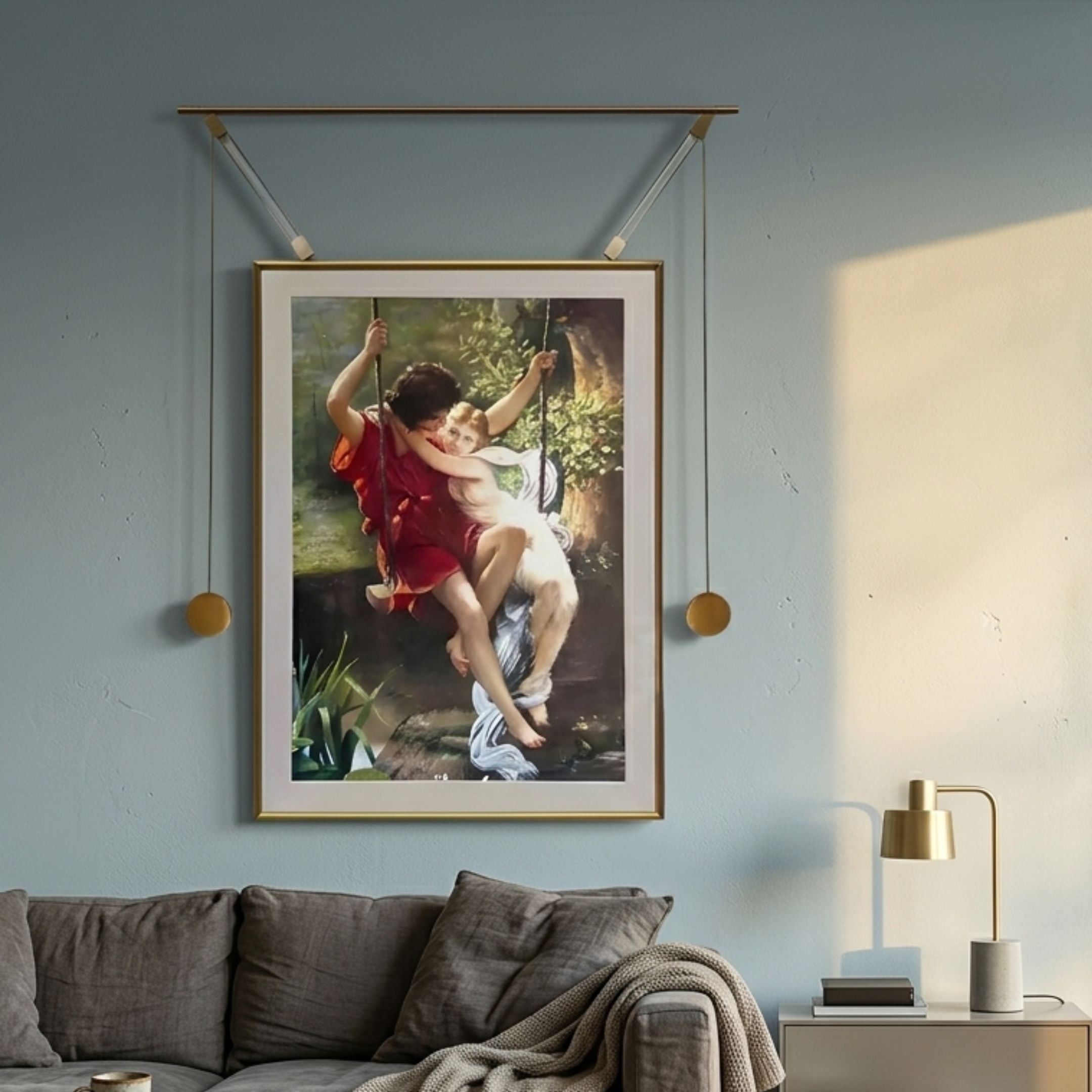 Giant Sculptures Aristo Romantic Swing gold frame wall art depicting two children on a garden swing, displayed above a grey sofa on a soft blue wall.