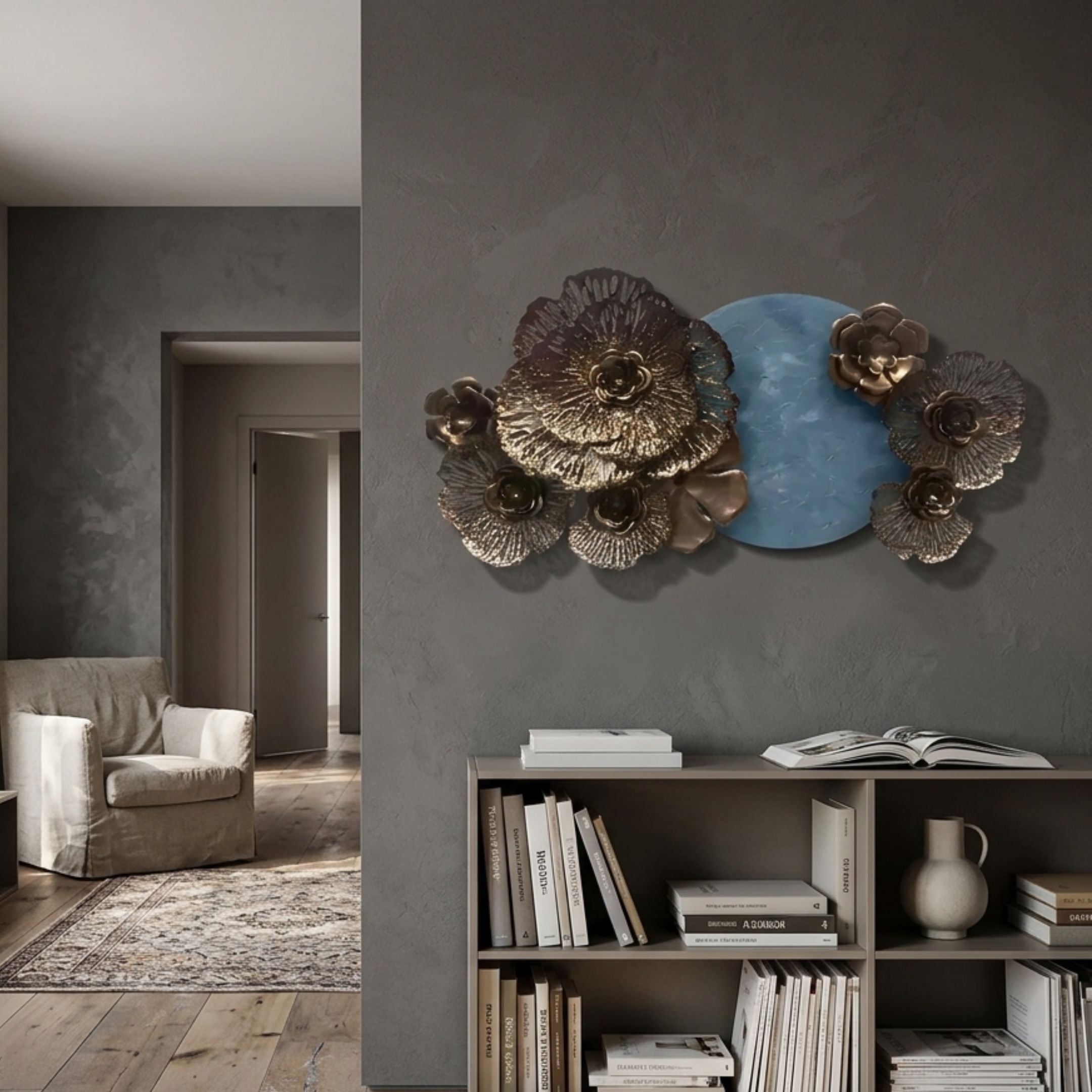 Luminis Bloom Blue Floral Metal Wall Art by Giant Sculptures mounted above a low bookshelf in a grey living room with armchair and rug nearby.