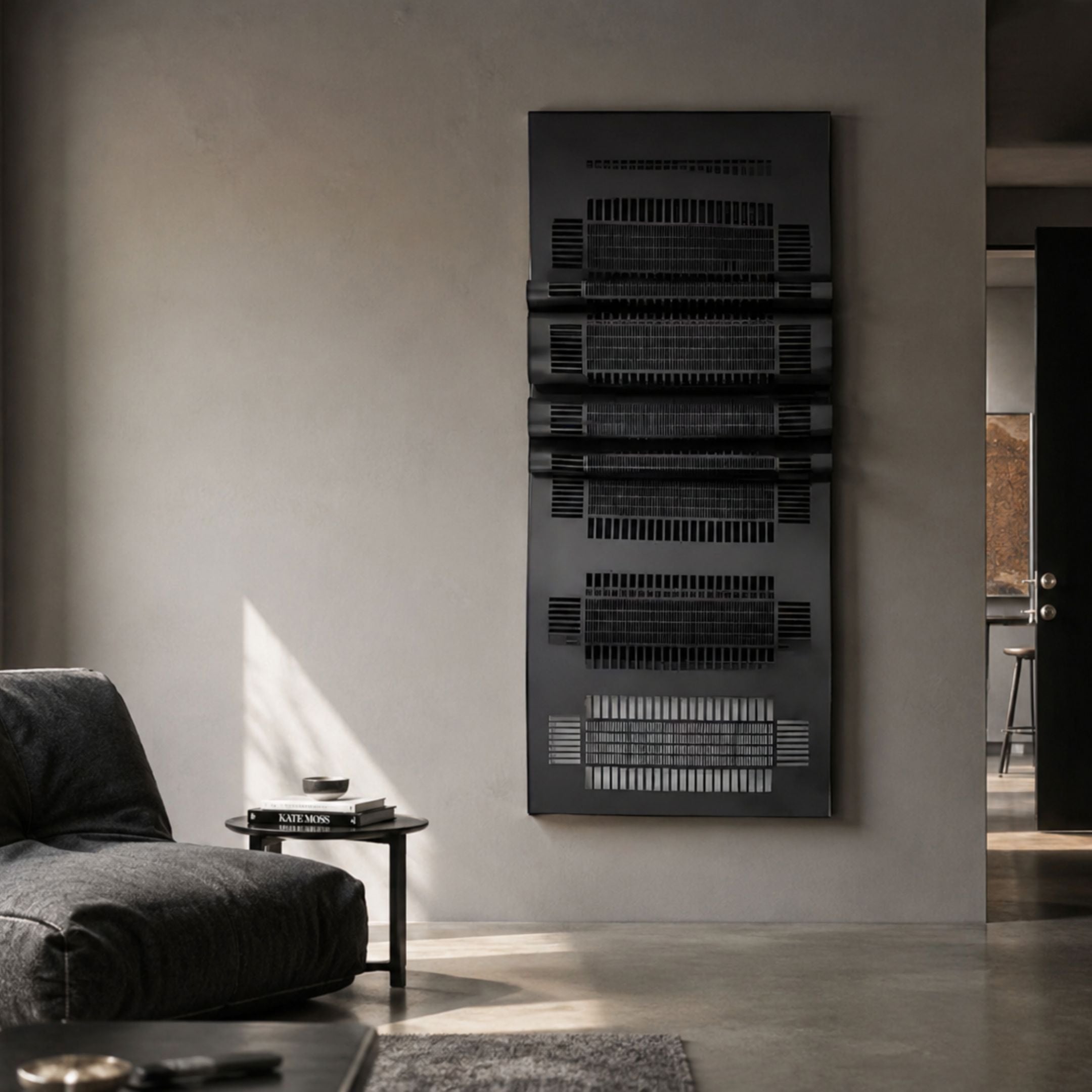 Strata Black Vertical Folded Grid Metal Wall Art by Giant Sculptures mounted on a pale wall in a modern living room with a grey lounge chair and side table.