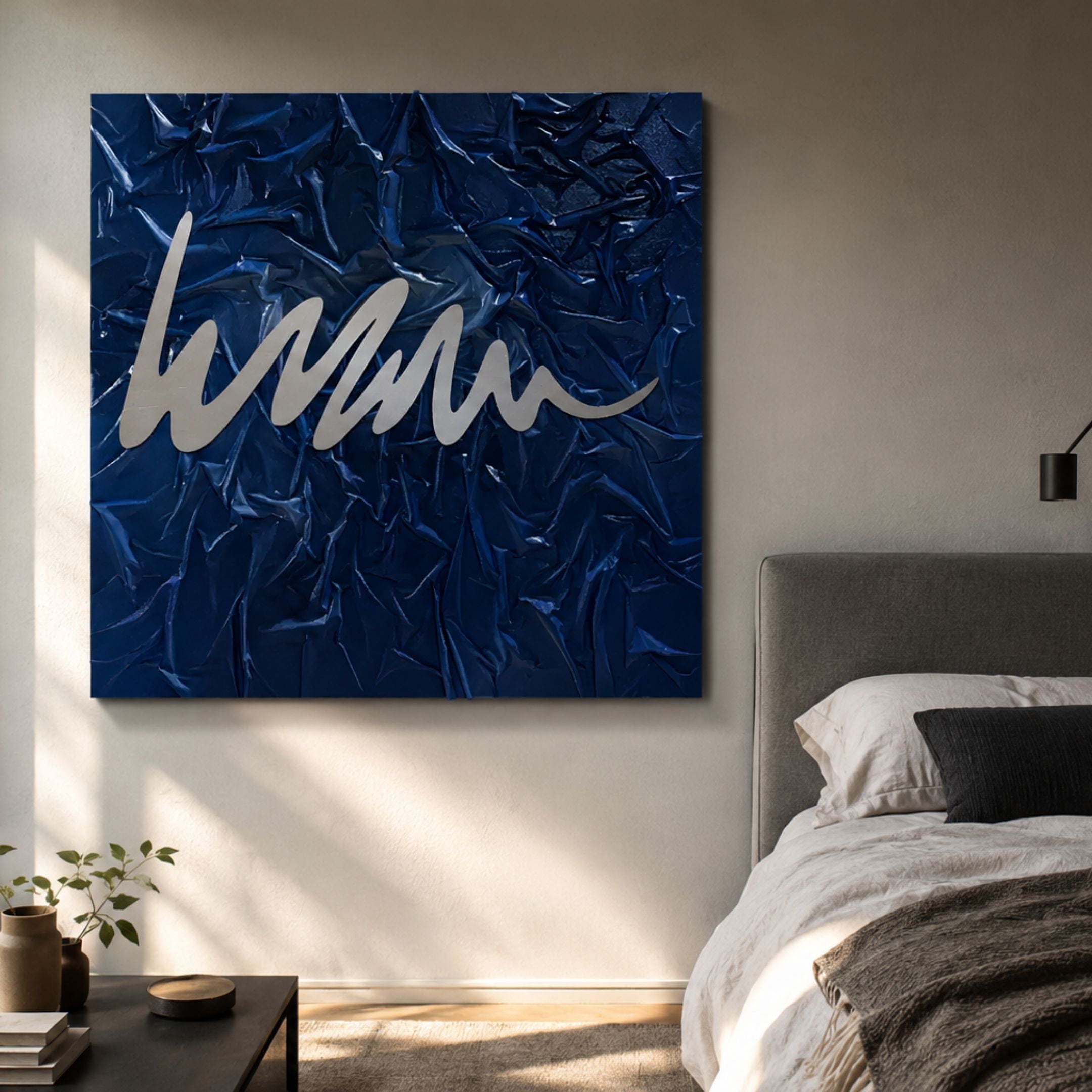 Plisse Midnight Blue Textured Abstract Wall Art by Giant Sculptures with a silver metallic squiggle on pleated navy fabric, mounted above a bed in a modern bedroom.