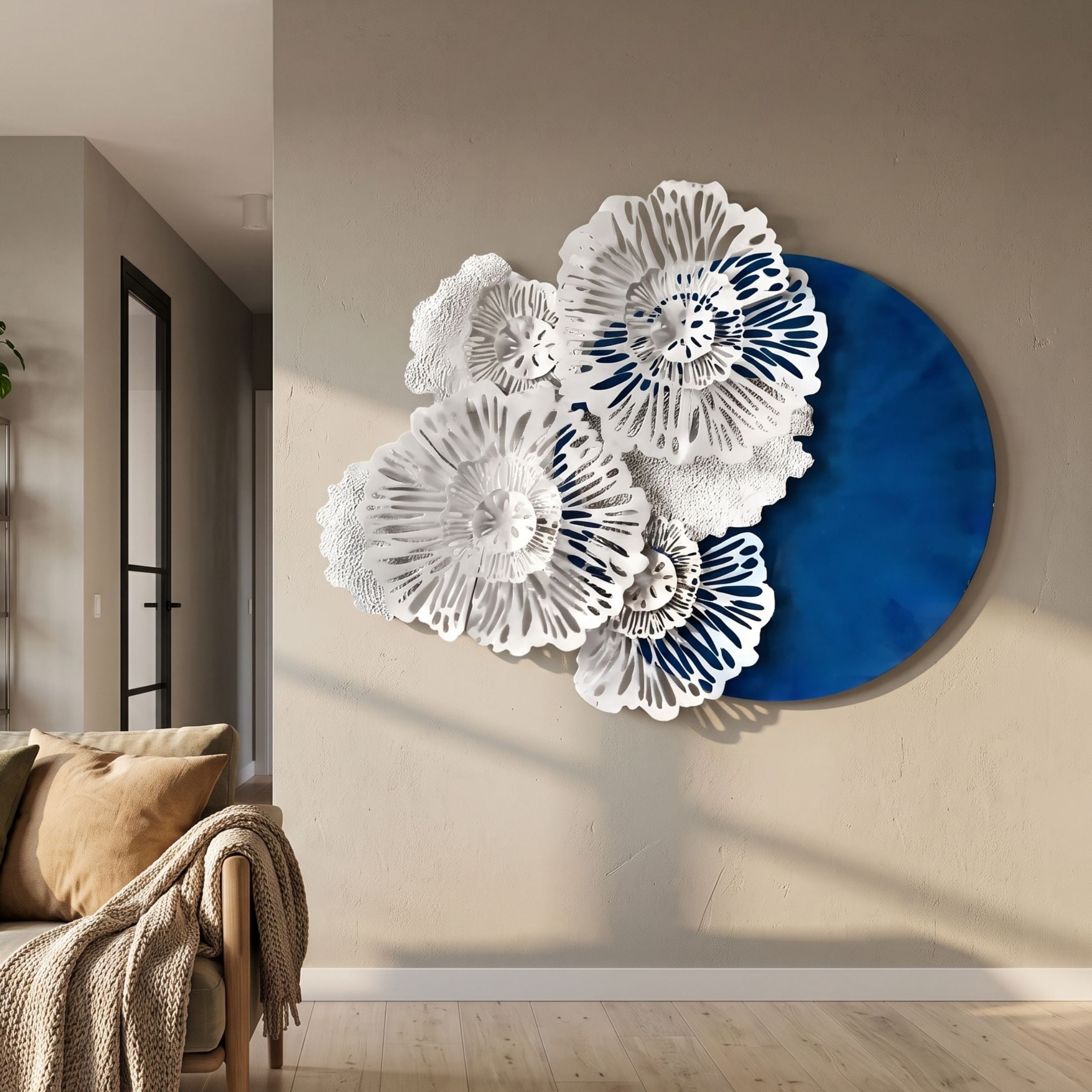 Aurum Flora White Petals Cobalt Blue Metal Wall Art with layered white floral cut-outs over a round blue disc, mounted above a beige sofa in a living room.