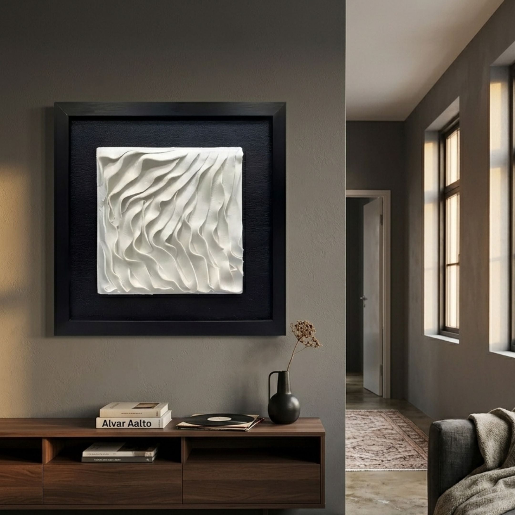 Harmonia 3D Wave Ceramic Wall Sculpture by Giant Sculptures, white sculpted relief in black frame, displayed above a walnut console in a grey hallway.