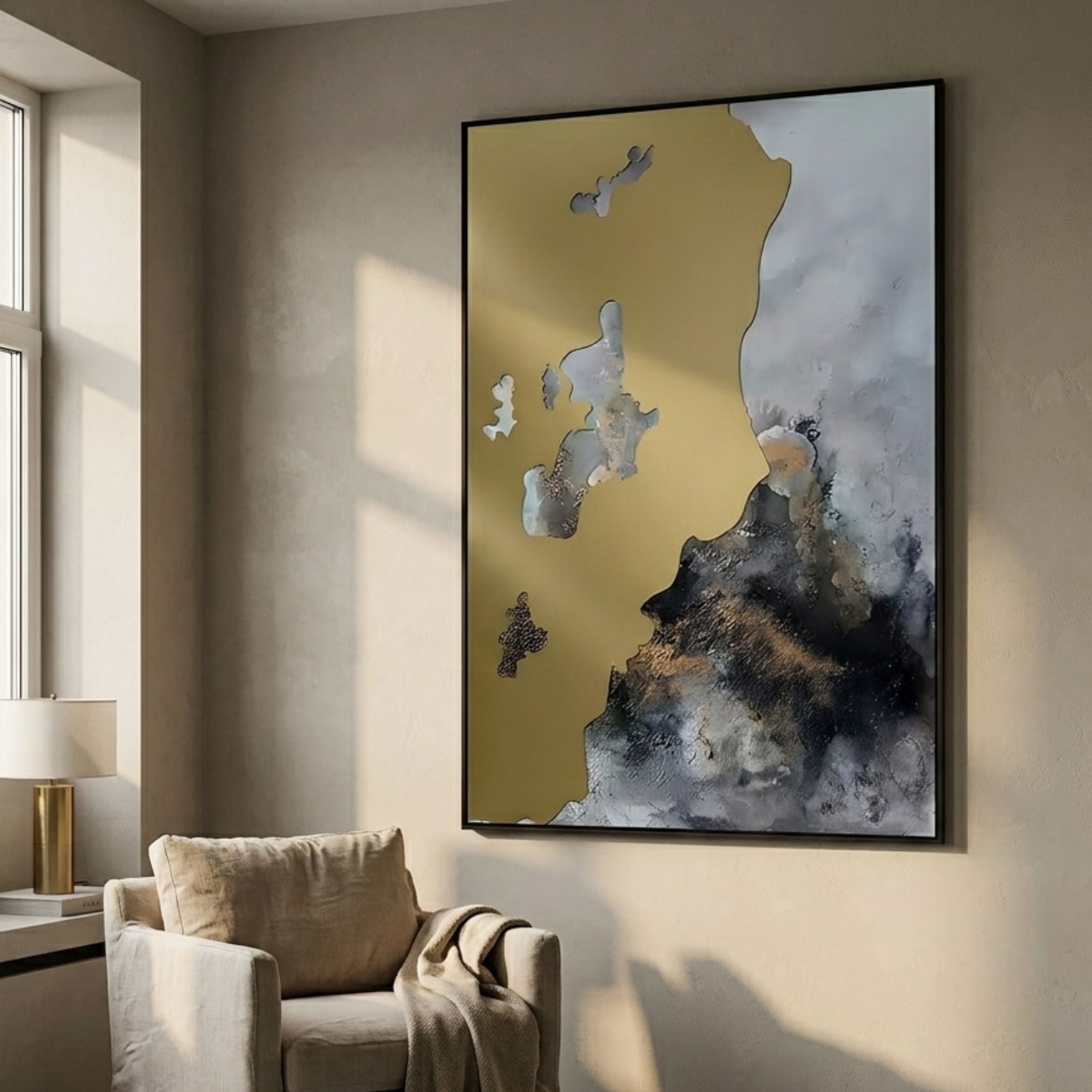 Astrid Gold Veil Textured Abstract Wall Art by Giant Sculptures, framed in black with gold, grey and black cloud-like forms, displayed above a cream armchair.