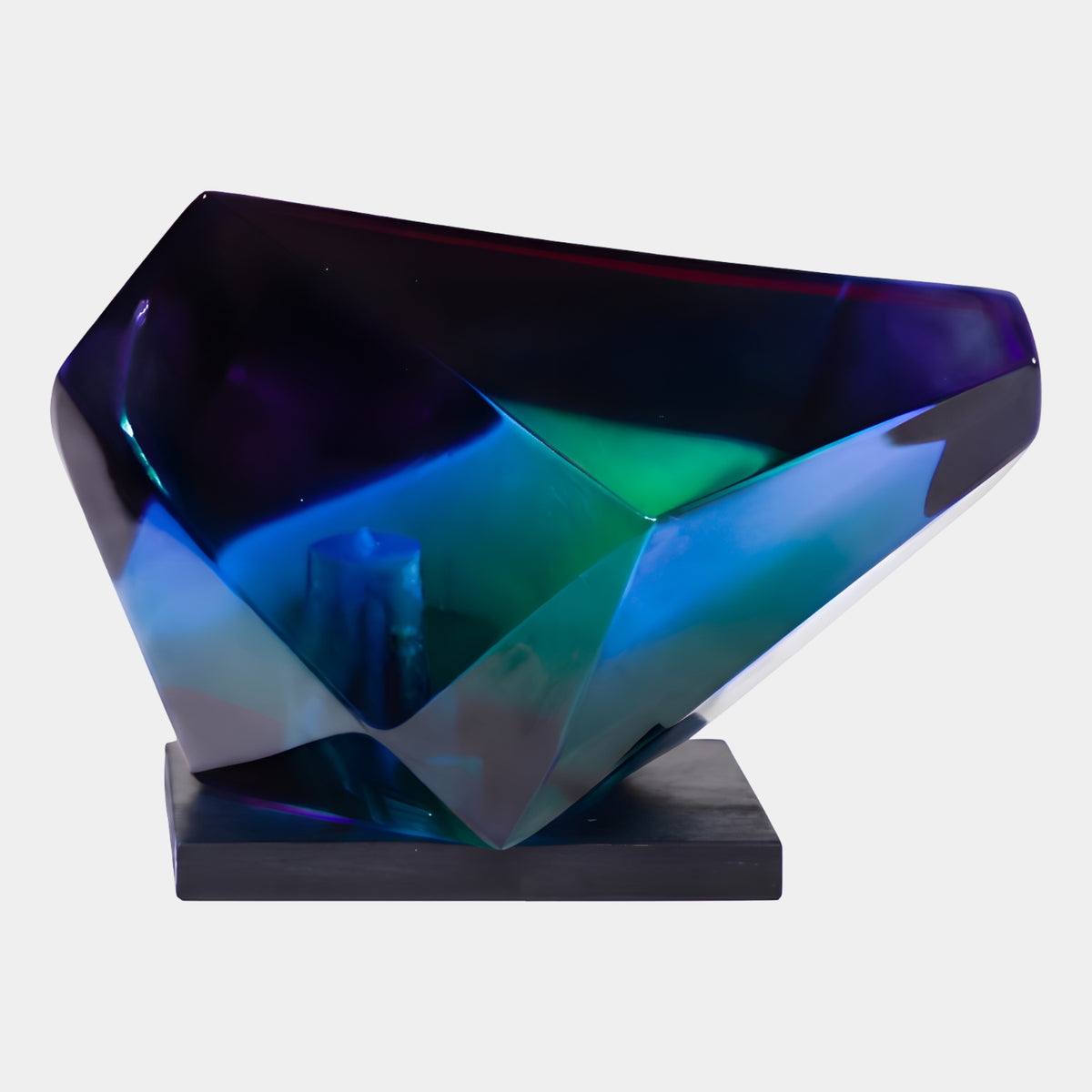 Blue & Violet Low Faceted Gem Resin Sculpture (16cm) by Giant Sculptures, a faceted resin gem shaded violet to blue to green, resting on its side on a black wood base against a plain white background.