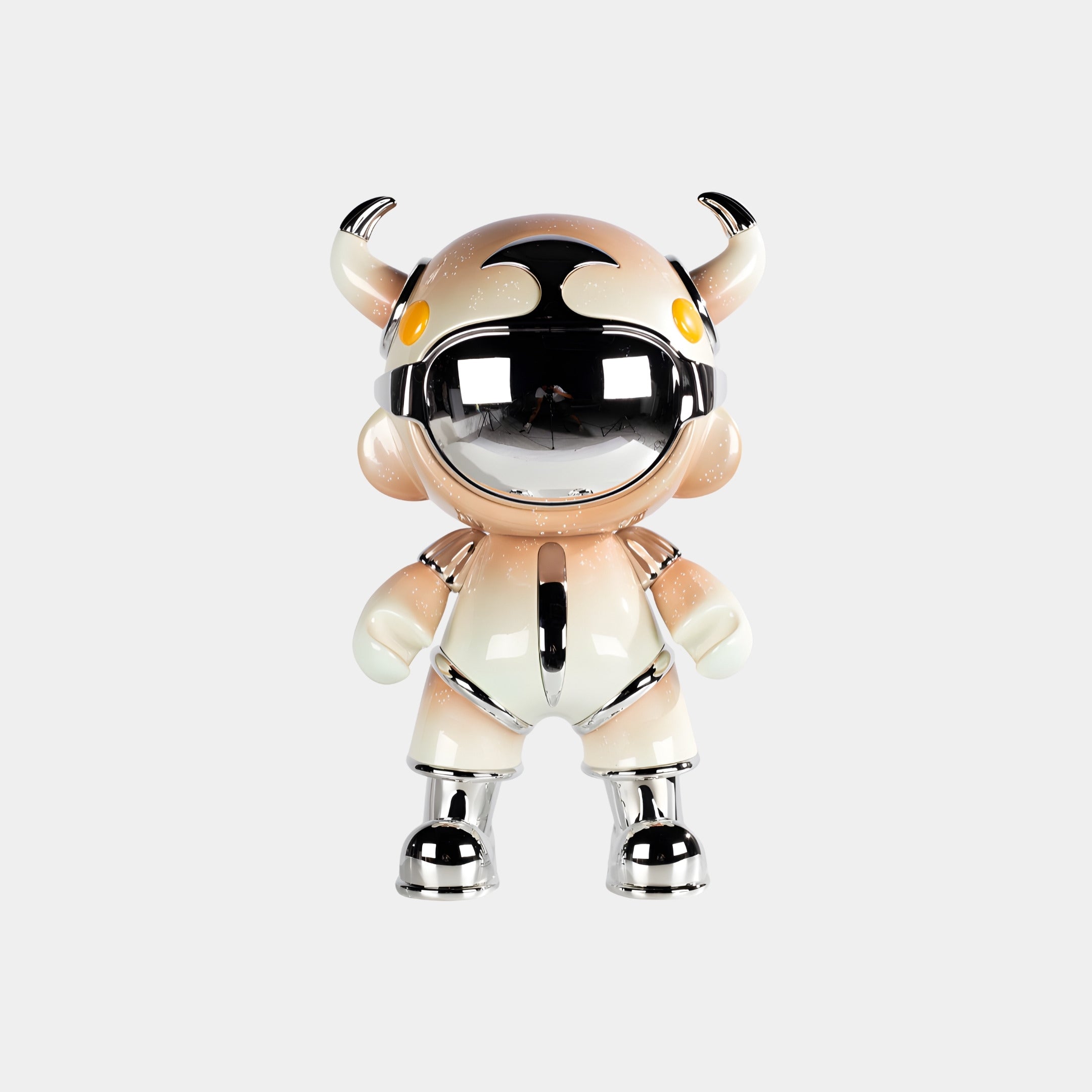 The Champagne Suit Astro Devil Figure (48cm) by Giant Sculptures features a metallic helmet, orange and white suit, small horns, round yellow eyes, and chrome accents on its feet, hands, and joints against a plain gray background.