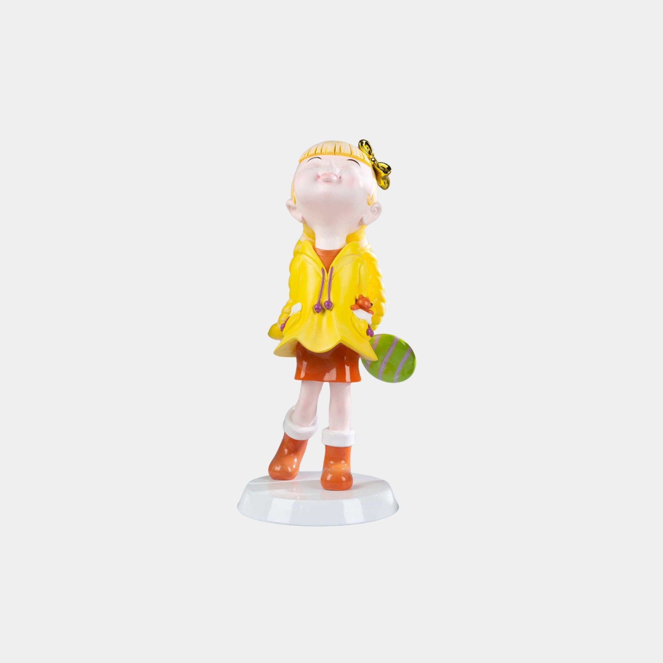The Sunbeam Yellow Lulabelle Figure by Giant Sculptures is a 20cm decorative sculpture featuring a cheerful girl in yellow and orange, holding a green ball with a butterfly atop her head—perfect for modern home decor.