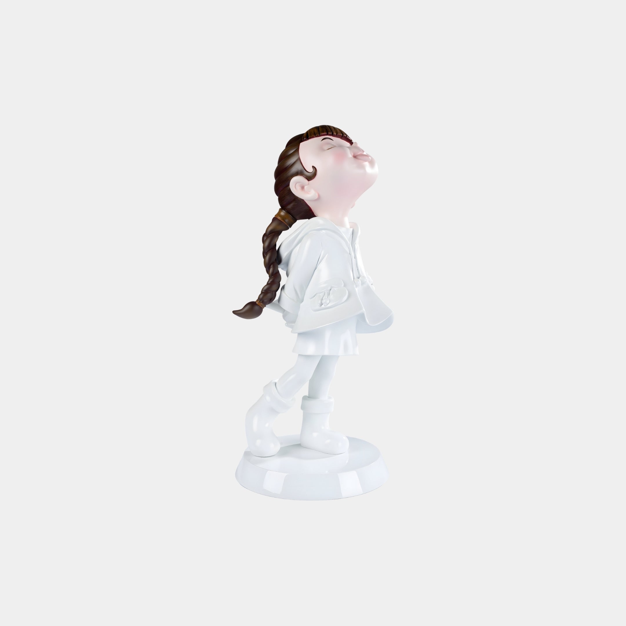 The Pure White Lulabelle Figure - 20cm by Giant Sculptures depicts a girl with brown braided hair in a raincoat and boots, gazing upward. Made from eco-friendly polyurethane, she stands out against a light gray background.