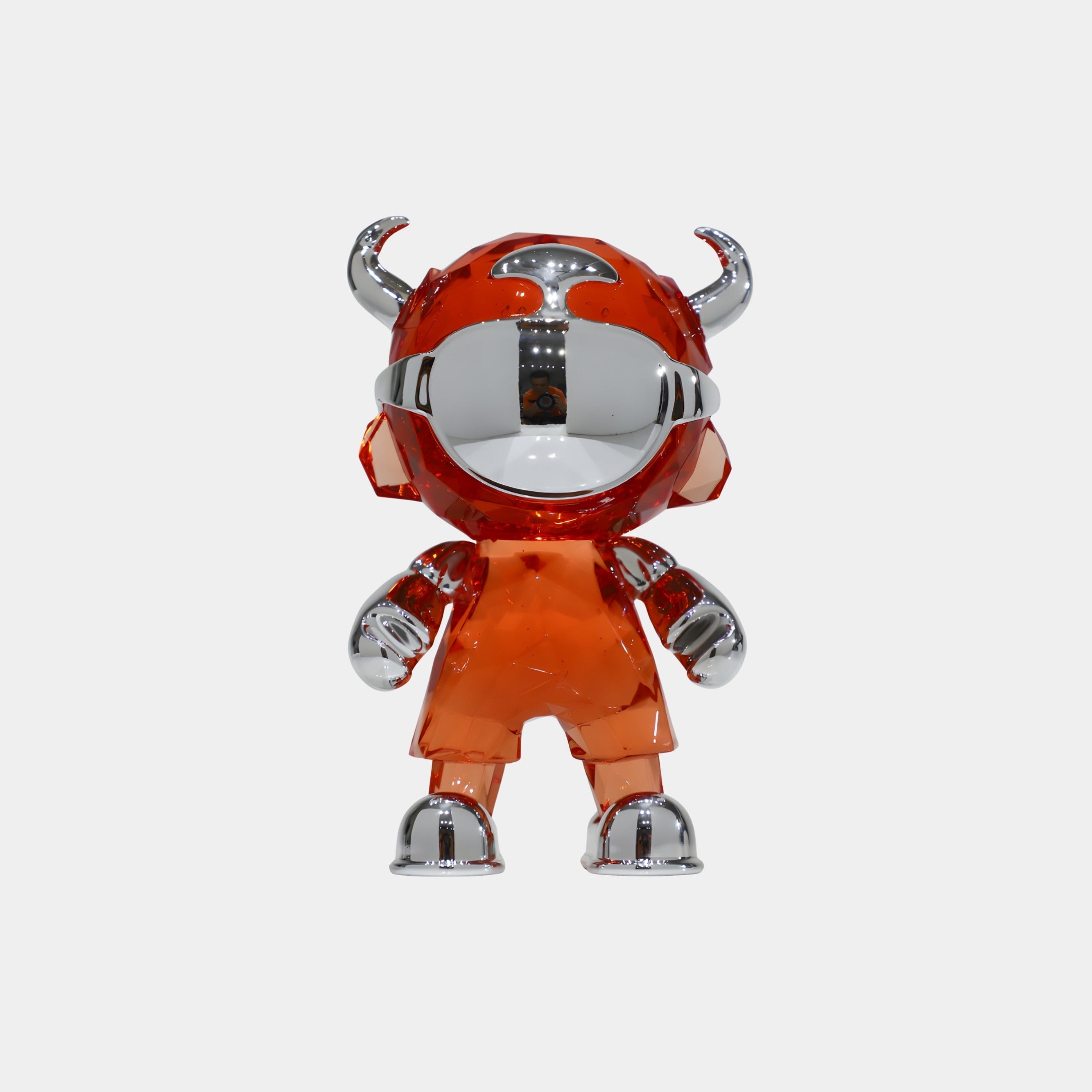 The Blaze Orange Chrome Astro Devil Figure - 15cm by Giant Sculptures is a designer toy with a shiny silver face, hands, and feet, wearing a translucent orange suit with helmet horns, set against a plain white background.