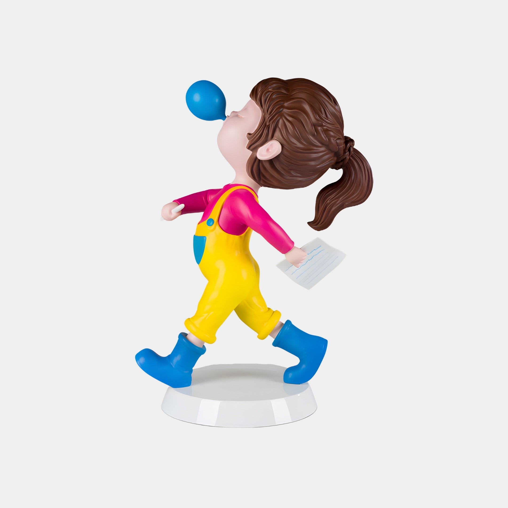 The Giant Sculptures Blue Bubble Popstride Figure - 56cm features a child with brown ponytail, pink shirt, yellow overalls, and blue boots, walking while blowing a blue bubble and holding papers, on a white base.