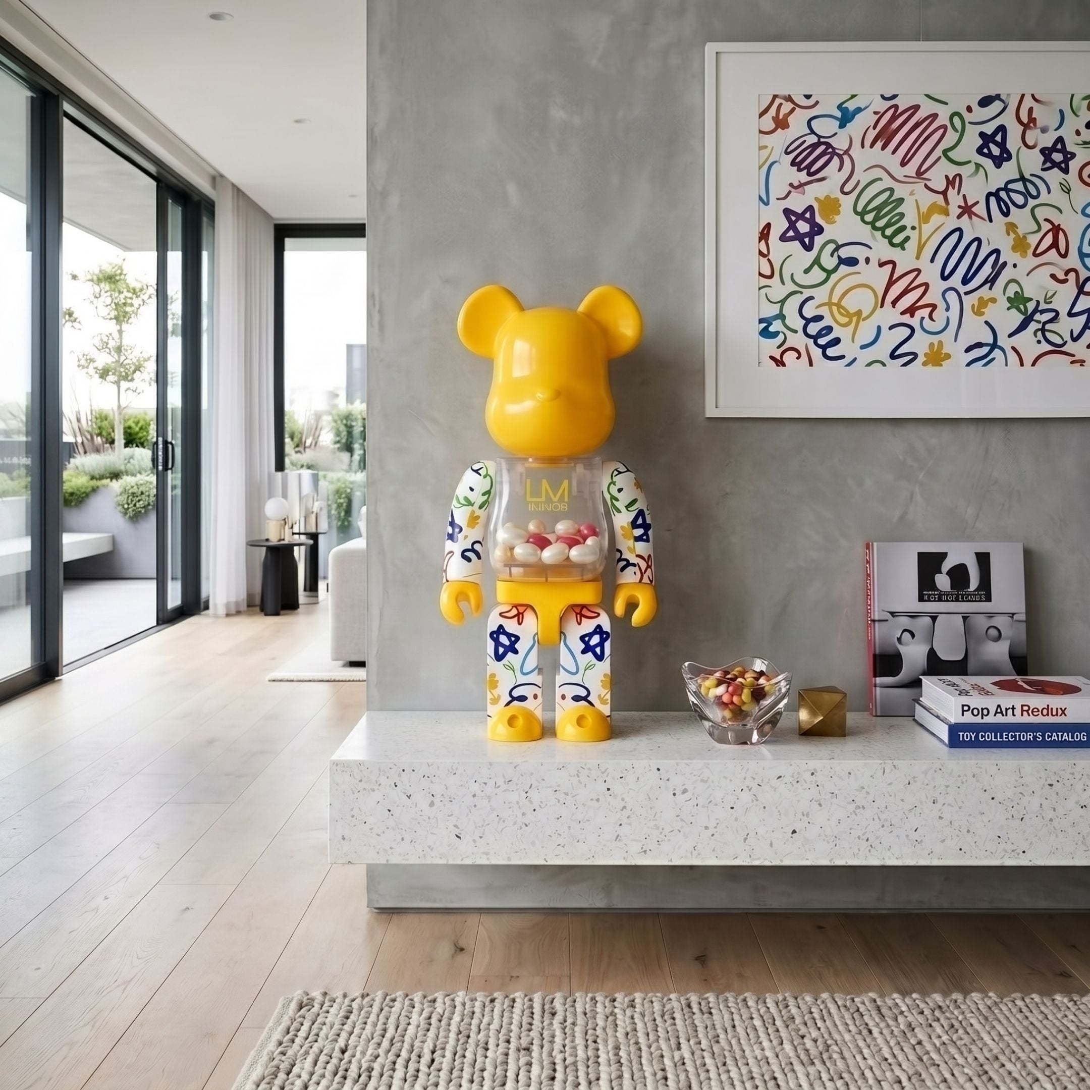Yellow Candy Doodle Bear Sculpture, 70cm, gloss yellow finish with colourful doodle patterns and a candy-filled chest, displayed on a shelf beside a pop art print in a living room.