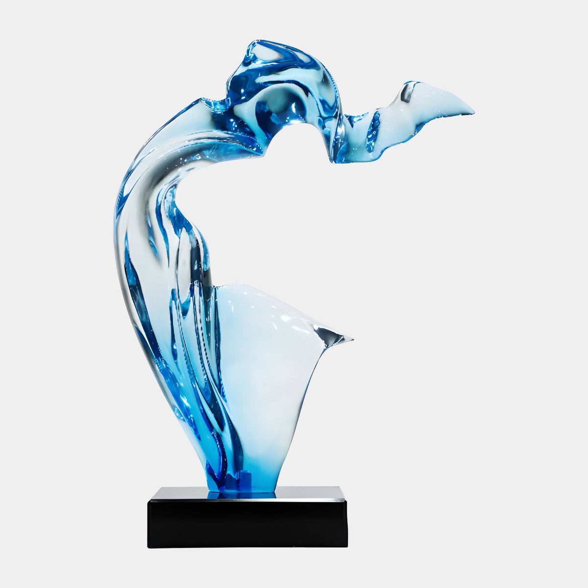 Graded Blue Arched Resin Sculpture - 60cm, an S-shaped blue resin form with a rippled crest and side fin, shading from dark blue to pale sky blue, on a black marble base against a plain light background.