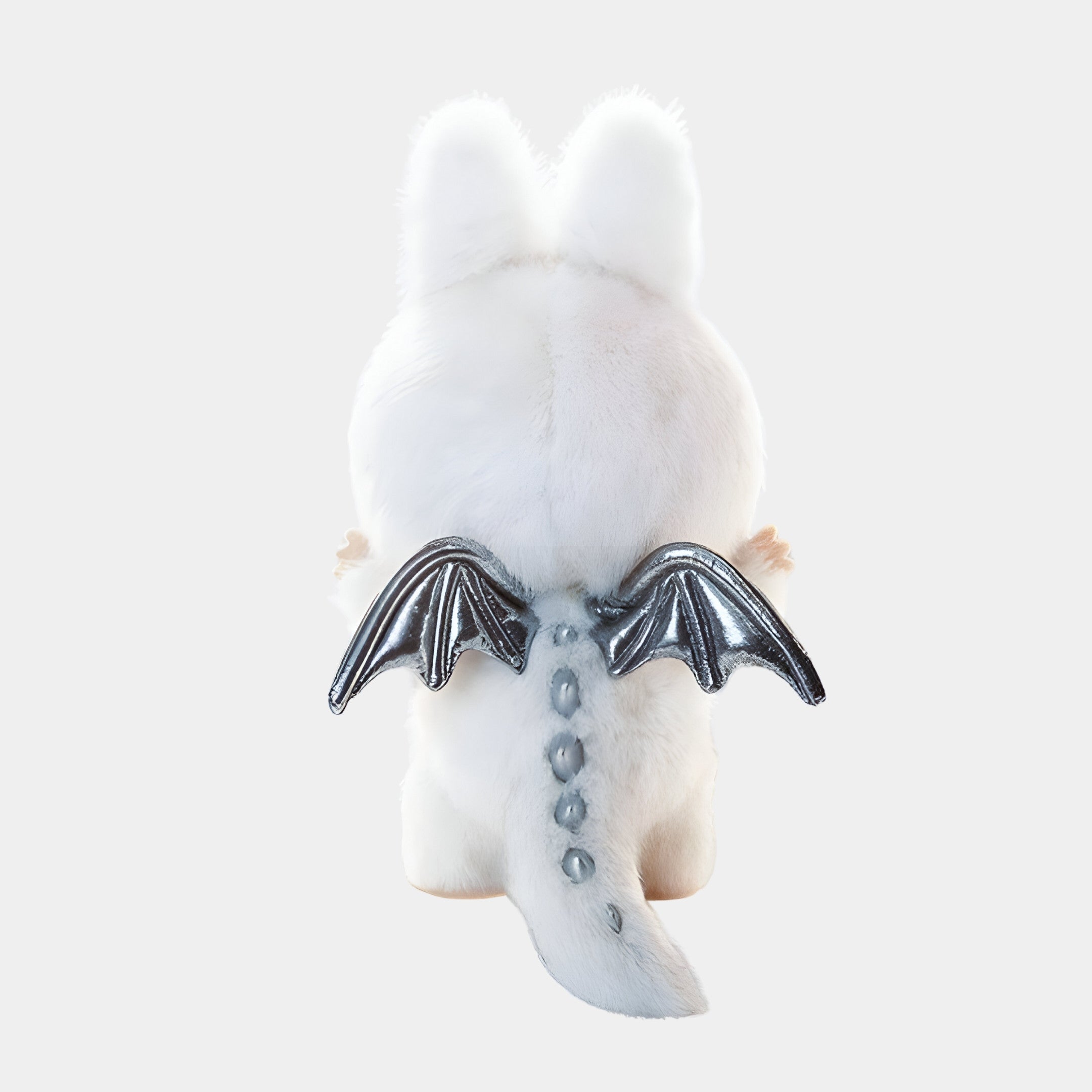 The Zimomo Angel White Labubu Sculpture by Giant Sculptures stands 100cm tall, featuring white faux fur, silver dragon wings, hand-painted details, and a row of soft blue-gray spikes along its tail and back. Set against a plain white background.