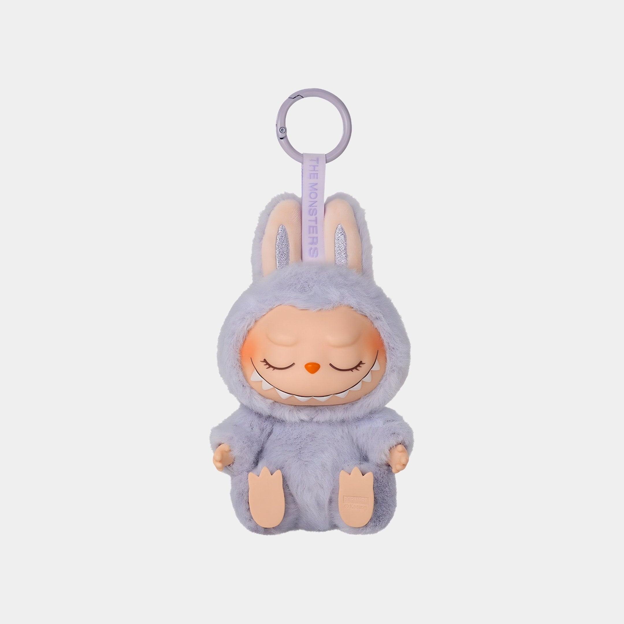 The Have A Seat Zizi Labubu Keychain Figure by Giant Sculptures is a 15cm plush faux fur keyring featuring a small doll in a fluffy lavender bunny suit, with closed eyes, a mischievous grin, and pale pink ear and foot accents.