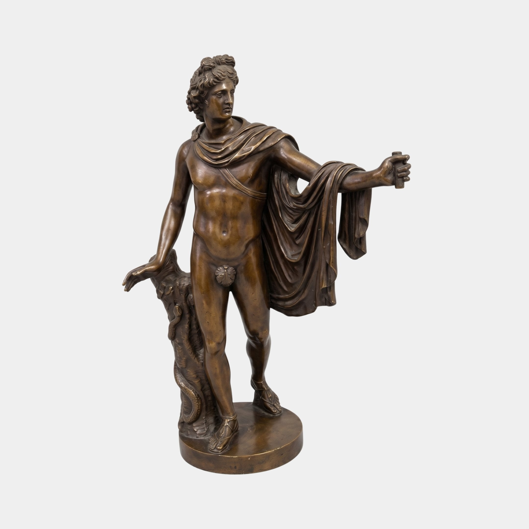 Classical Nude Male Figure Bronze Sculpture by Giant Sculptures in contrapposto pose with draped cloak and tree trunk support, warm brown patina, plain background.