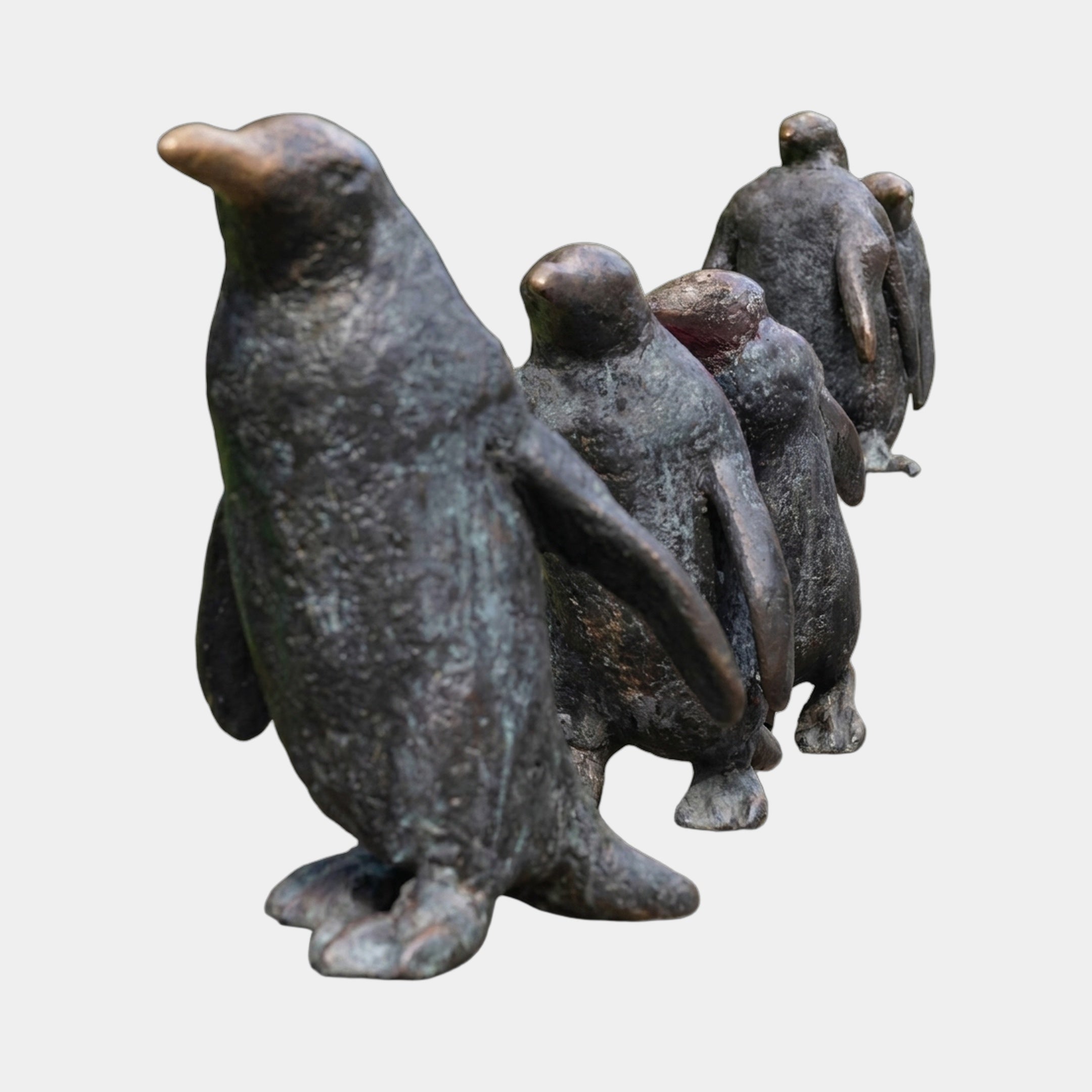 Contemporary Life-Size Penguin Group Bronze Sculpture by Giant Sculptures, showing a line of penguins with dark patina and golden-brown beaks on a plain background.