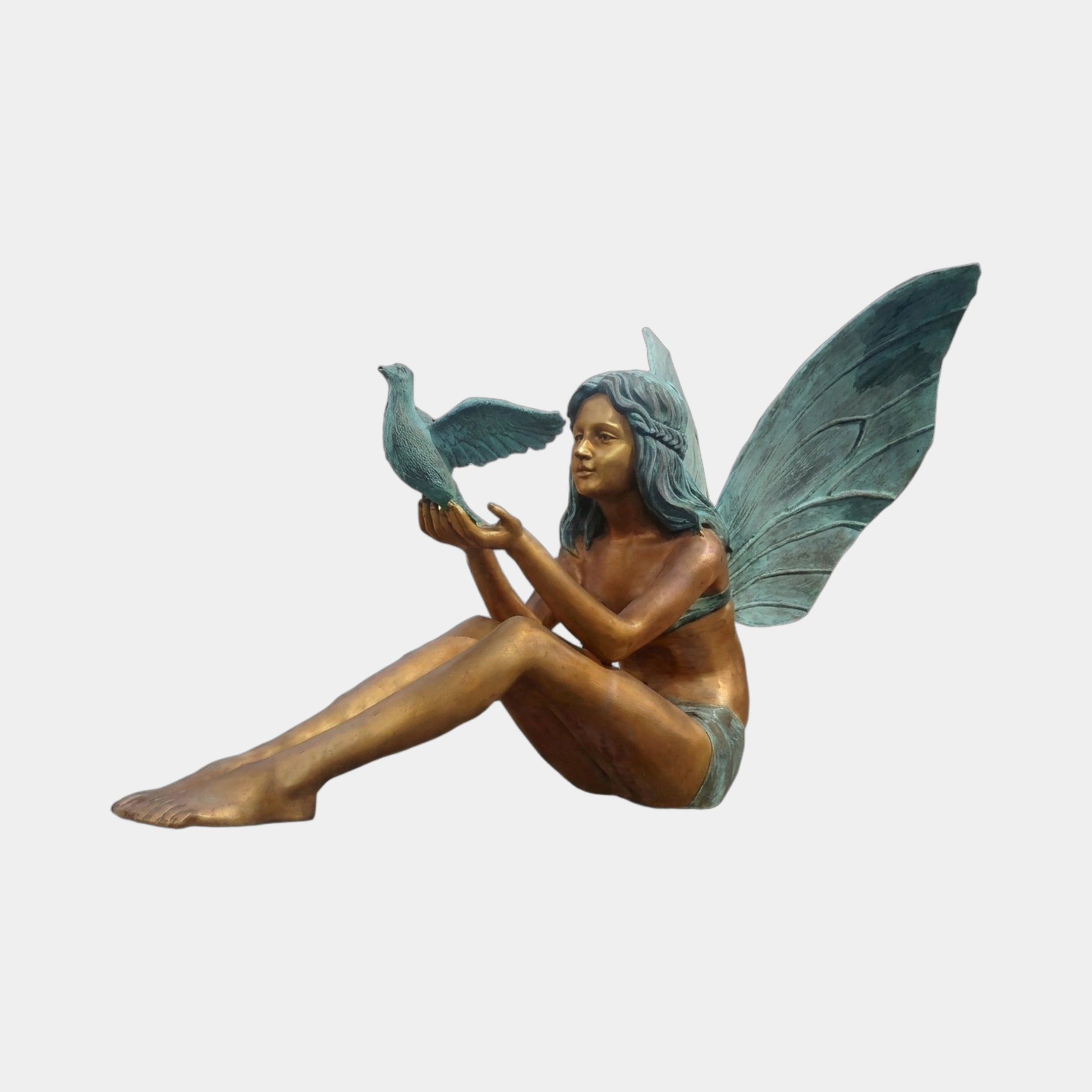 Contemporary Seated Fairy Girl with Dove Bronze Sculpture by Giant Sculptures, seated nude figure with verdigris wings holding a dove, on a plain background.