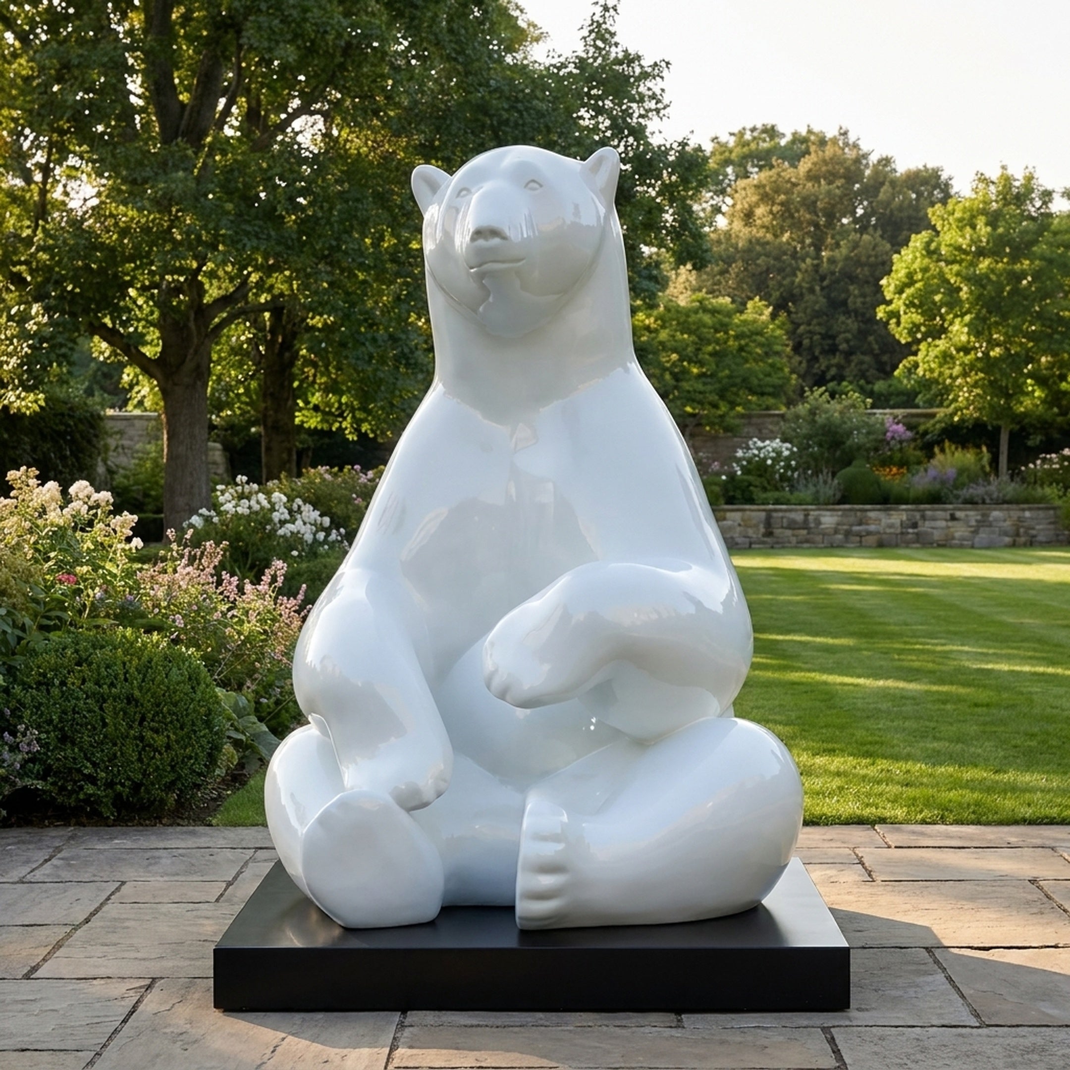 Giant Sculptures Giant Contemporary Polar Bear Bronze Sculpture 240cm in high-gloss white, seated with crossed legs on a black plinth in a sunlit garden.