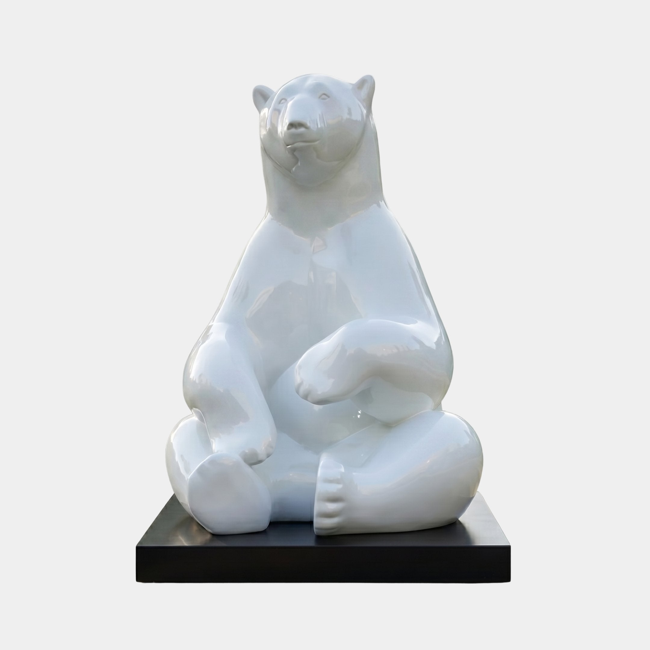 Giant Contemporary Polar Bear Bronze Sculpture by Giant Sculptures, seated upright with crossed legs in a high-gloss white finish, on a black rectangular plinth.