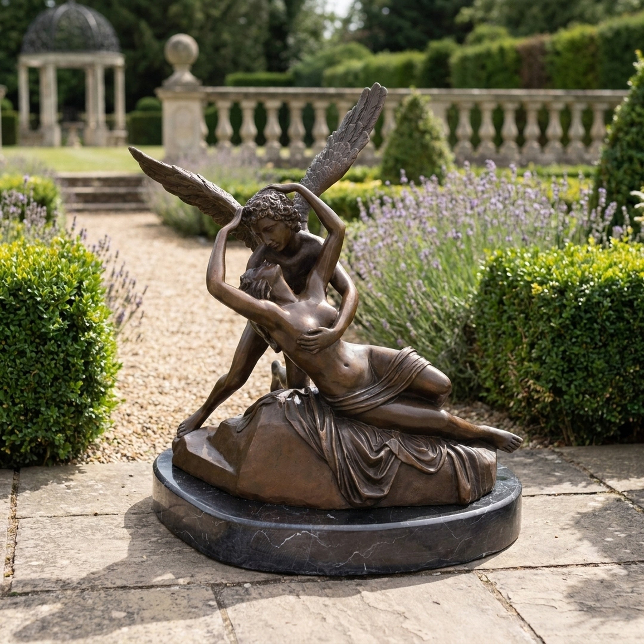 Large Classical Cupid and Psyche Bronze Sculpture by Giant Sculptures, warm brown patina on a black granite base, displayed on a formal garden path.
