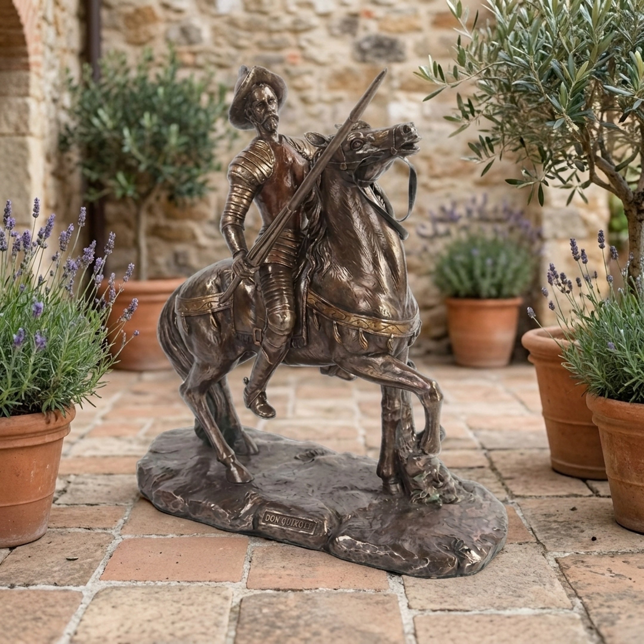 Large Classical Don Quixote on Rearing Horse Bronze Sculpture by Giant Sculptures displayed on a stone courtyard with lavender pots and olive trees.
