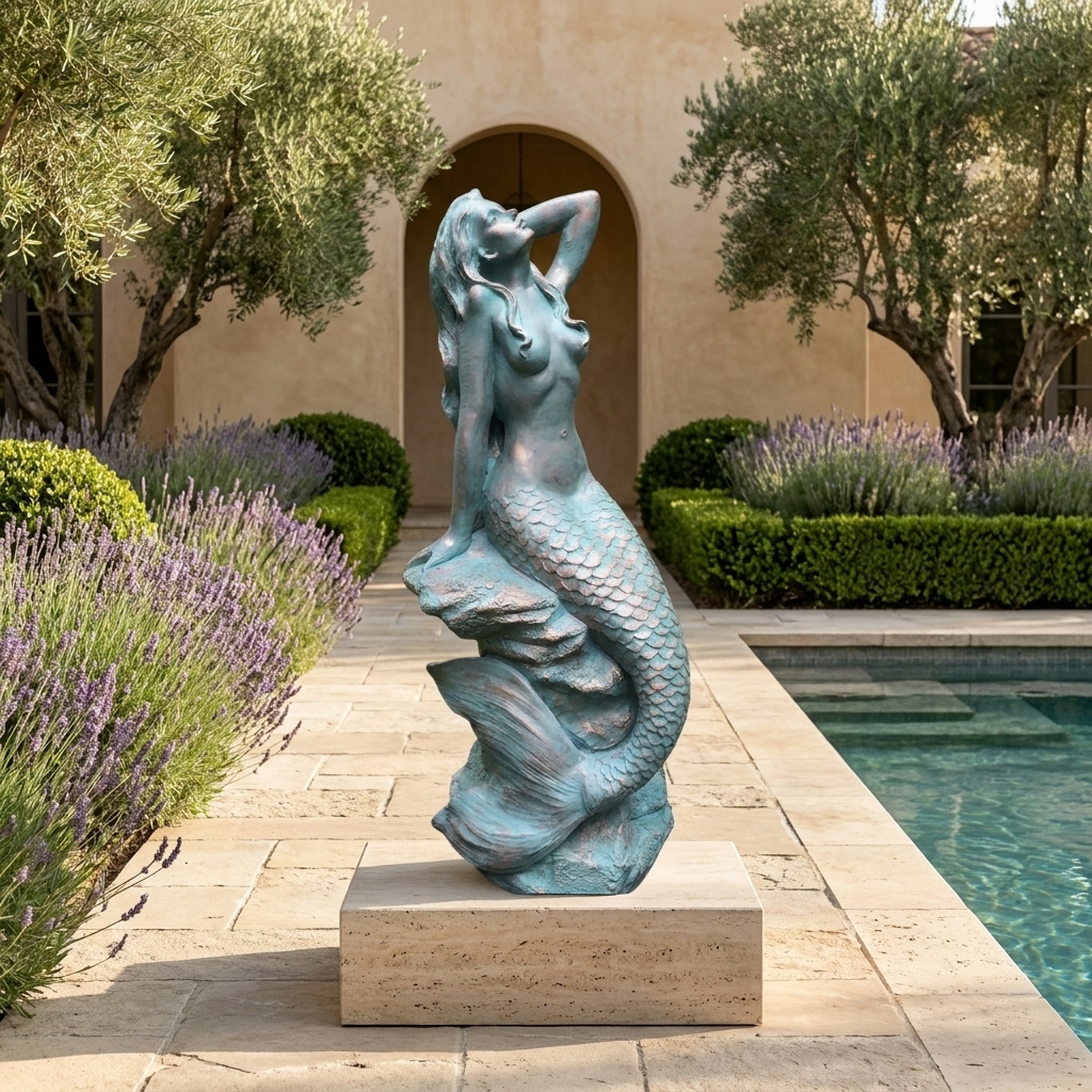 Large Classical Reclining Mermaid Bronze Sculpture by Giant Sculptures with verdigris patina, displayed on a stone plinth beside a poolside lavender garden.