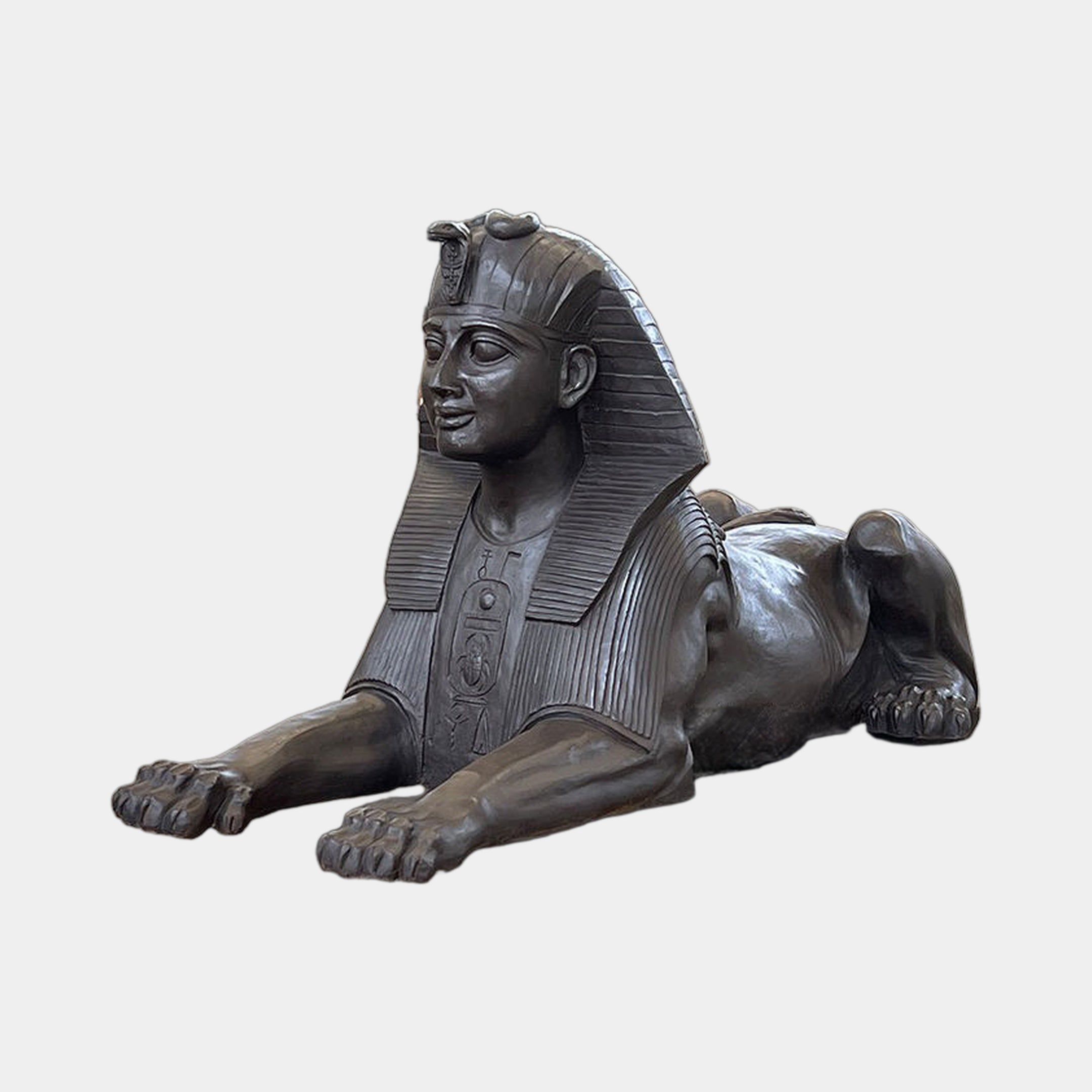 Large Classical Recumbent Egyptian Sphinx Bronze Sculpture by Giant Sculptures, 180cm, dark patina with nemes headdress and hieroglyphic chest panel, plain background.