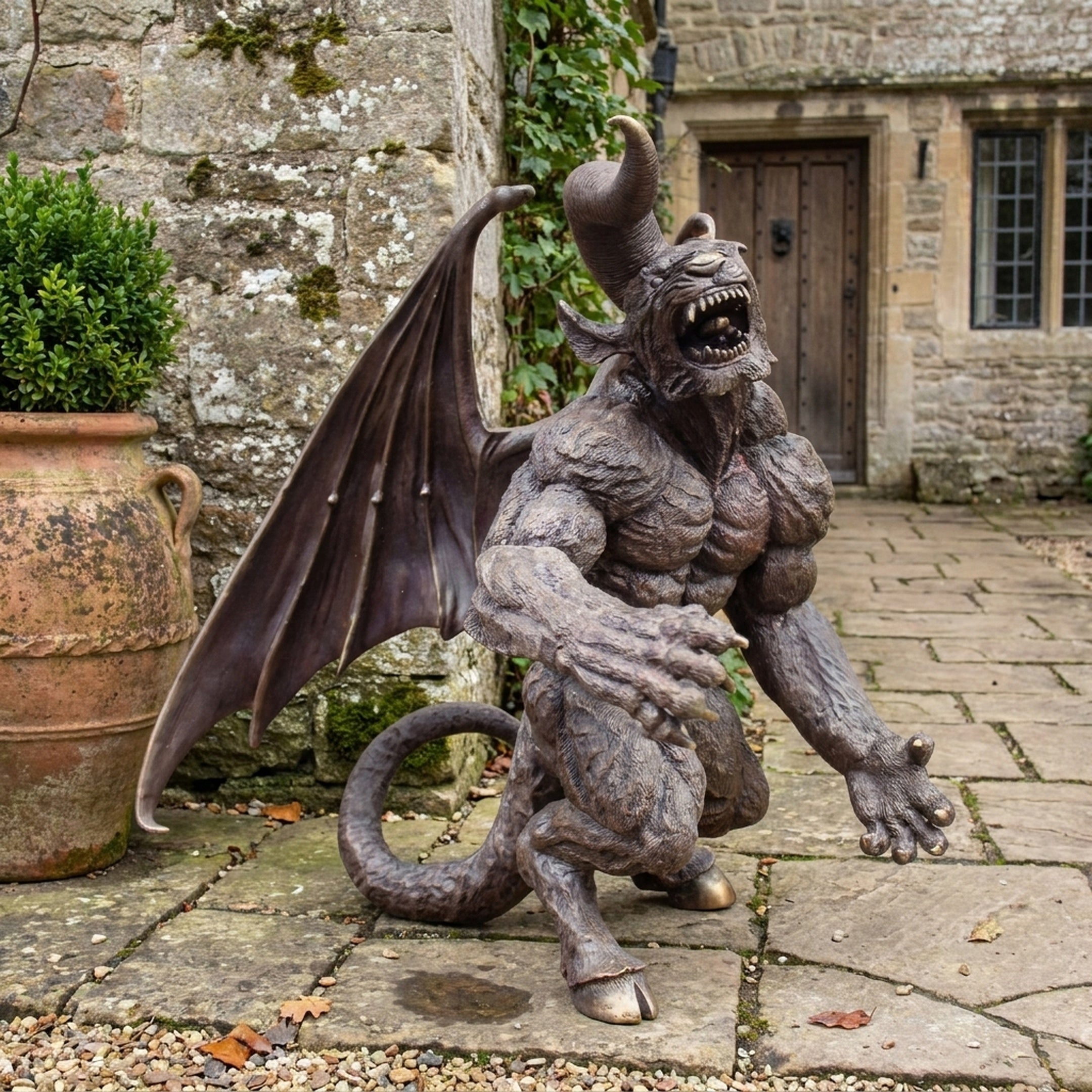 Giant Sculptures' 150cm Large Contemporary Crouching Gargoyle Demon Bronze Sculpture with spread wings and curled tail, displayed on stone paving beside a terracotta urn.