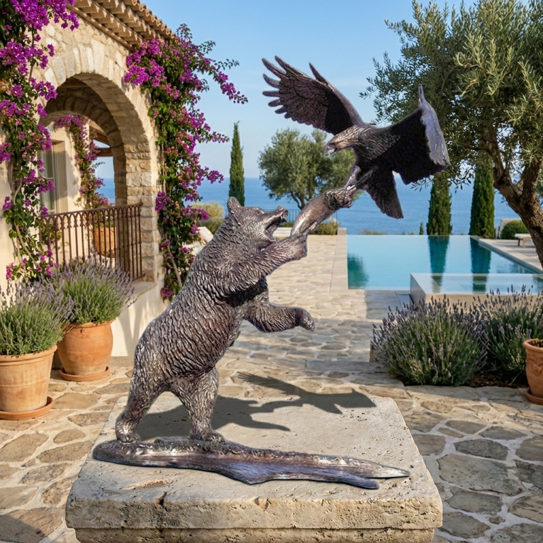 Large Traditional Rearing Bear and Eagle Bronze Sculpture by Giant Sculptures displayed on a stone patio with lavender, bougainvillea, and a sea-view pool.