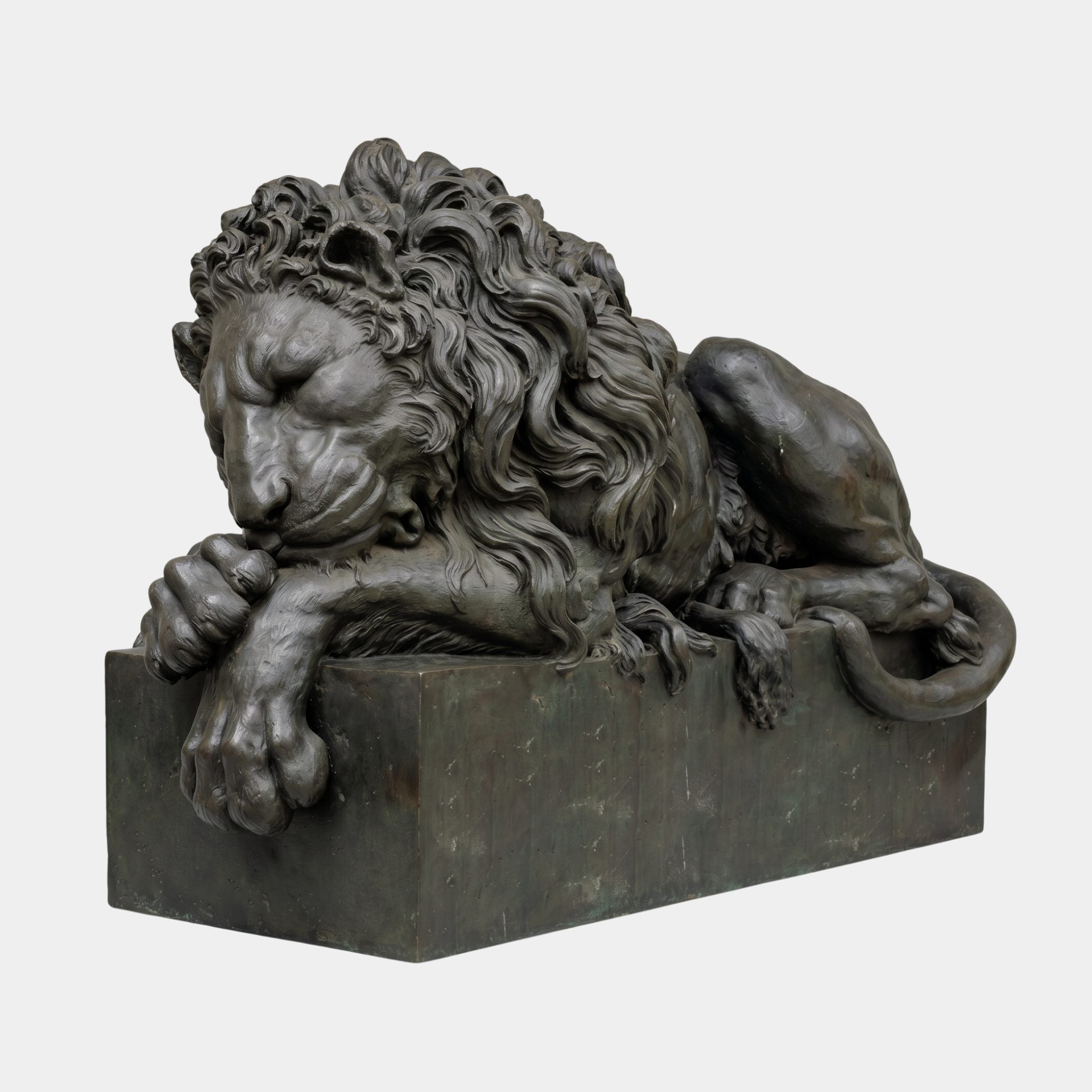 Life-Size Classical Recumbent Lion Bronze Sculpture by Giant Sculptures, shown in side view with head resting on crossed forepaws atop a rectangular plinth.