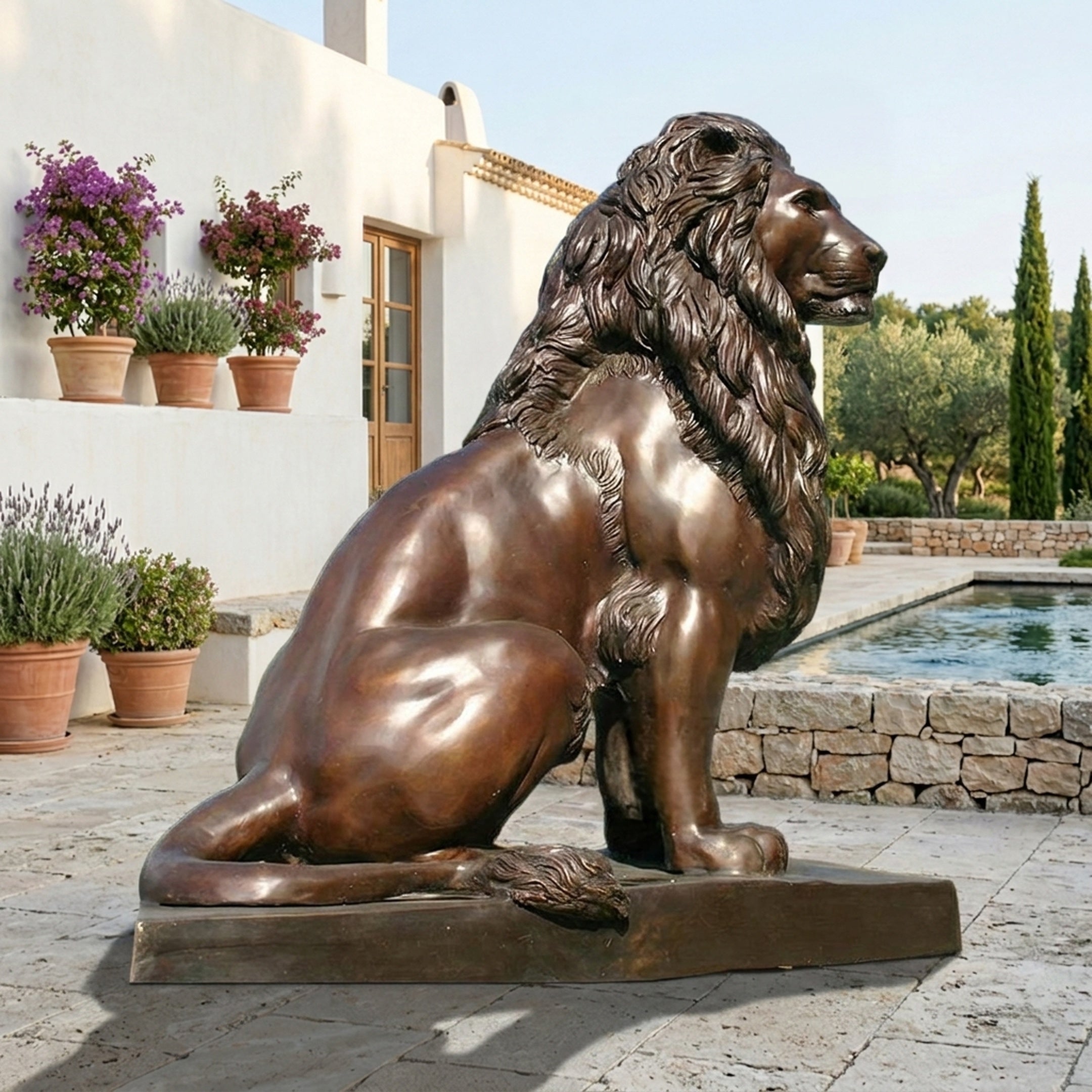 Giant Sculptures Life-Size Classical Seated Lion Bronze Sculpture 260cm in warm brown patina, shown in profile beside a poolside terrace with potted lavender.