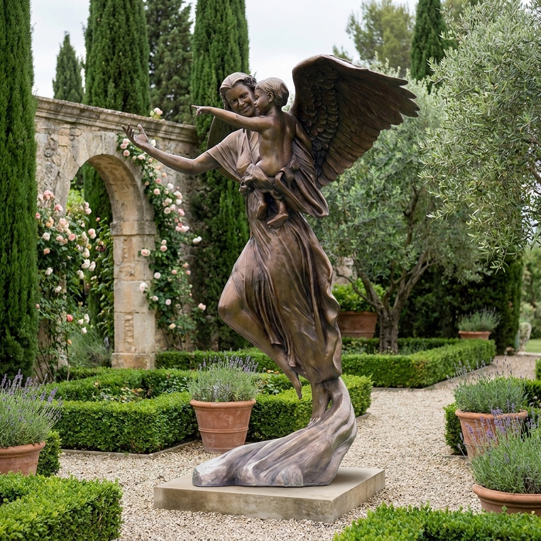 Life-Size Classical Winged Angel Bronze Sculpture by Giant Sculptures, shown holding a child aloft in a formal garden with stone arch and lavender borders.