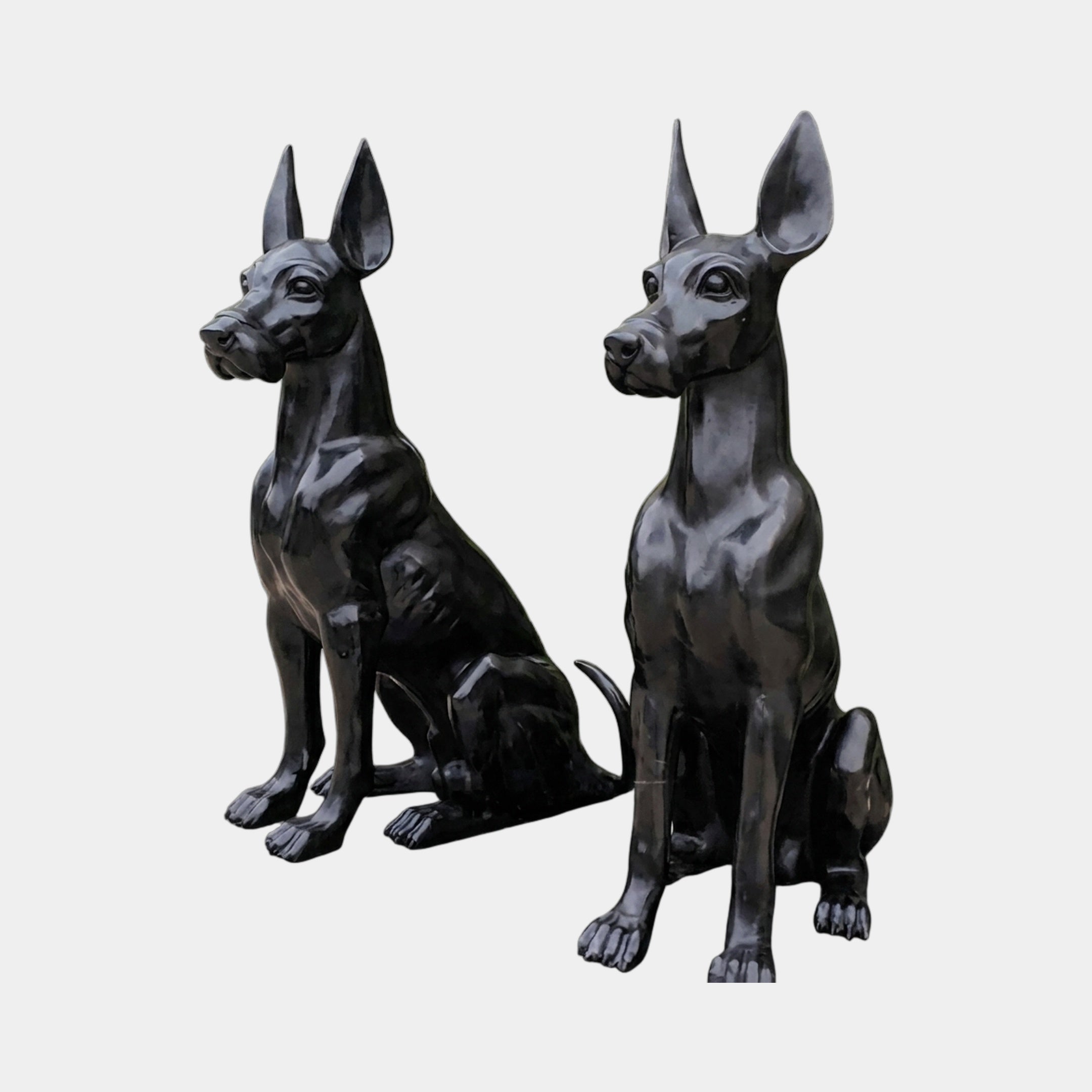 Life-Size Contemporary Seated Doberman Pair Bronze Sculpture by Giant Sculptures, 100cm, in glossy black with alert cropped ears, shown on a plain background.