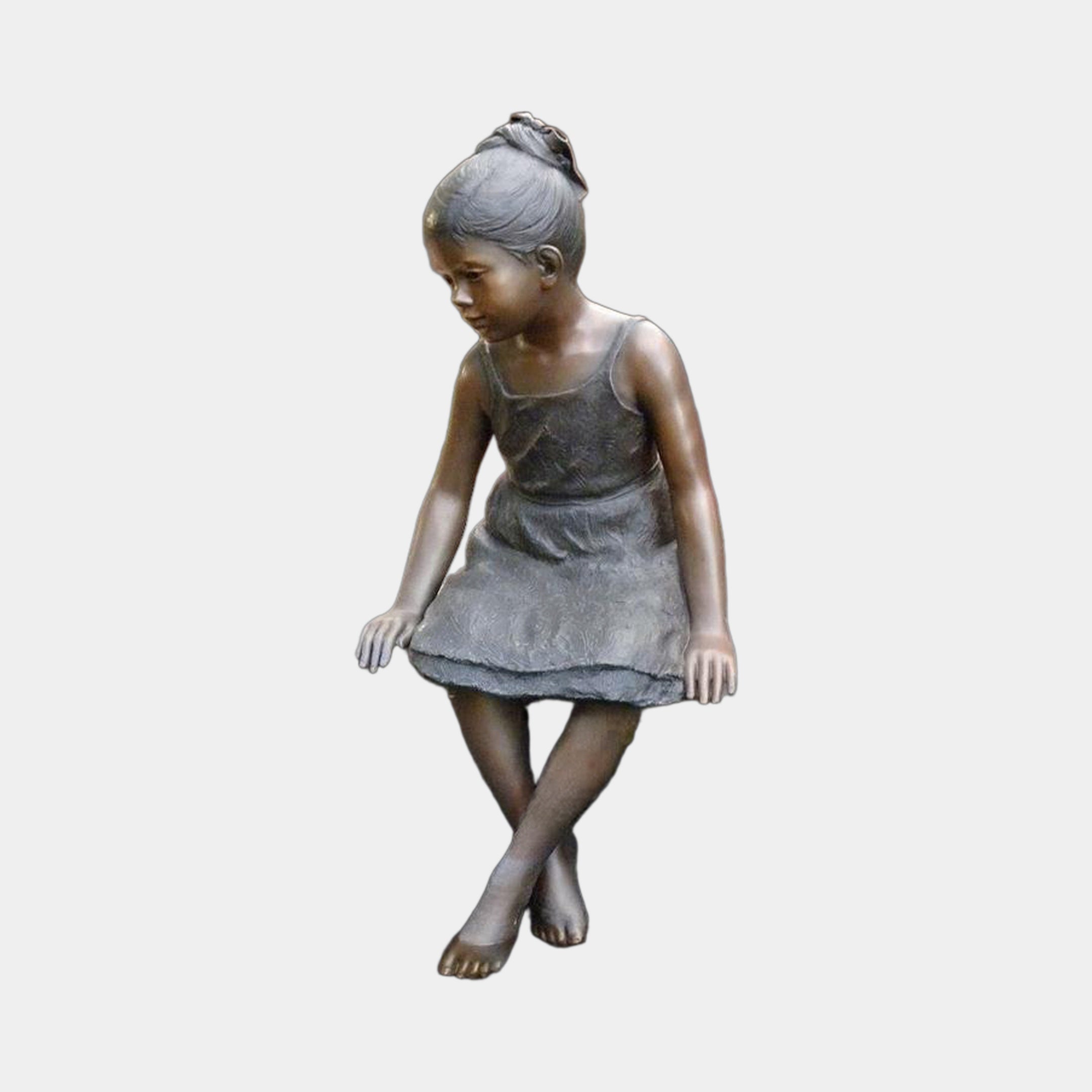 Life-Size Contemporary Sitting Girl Bronze Sculpture by Giant Sculptures, 130cm, shown seated with legs crossed and gaze lowered, against a plain grey background.
