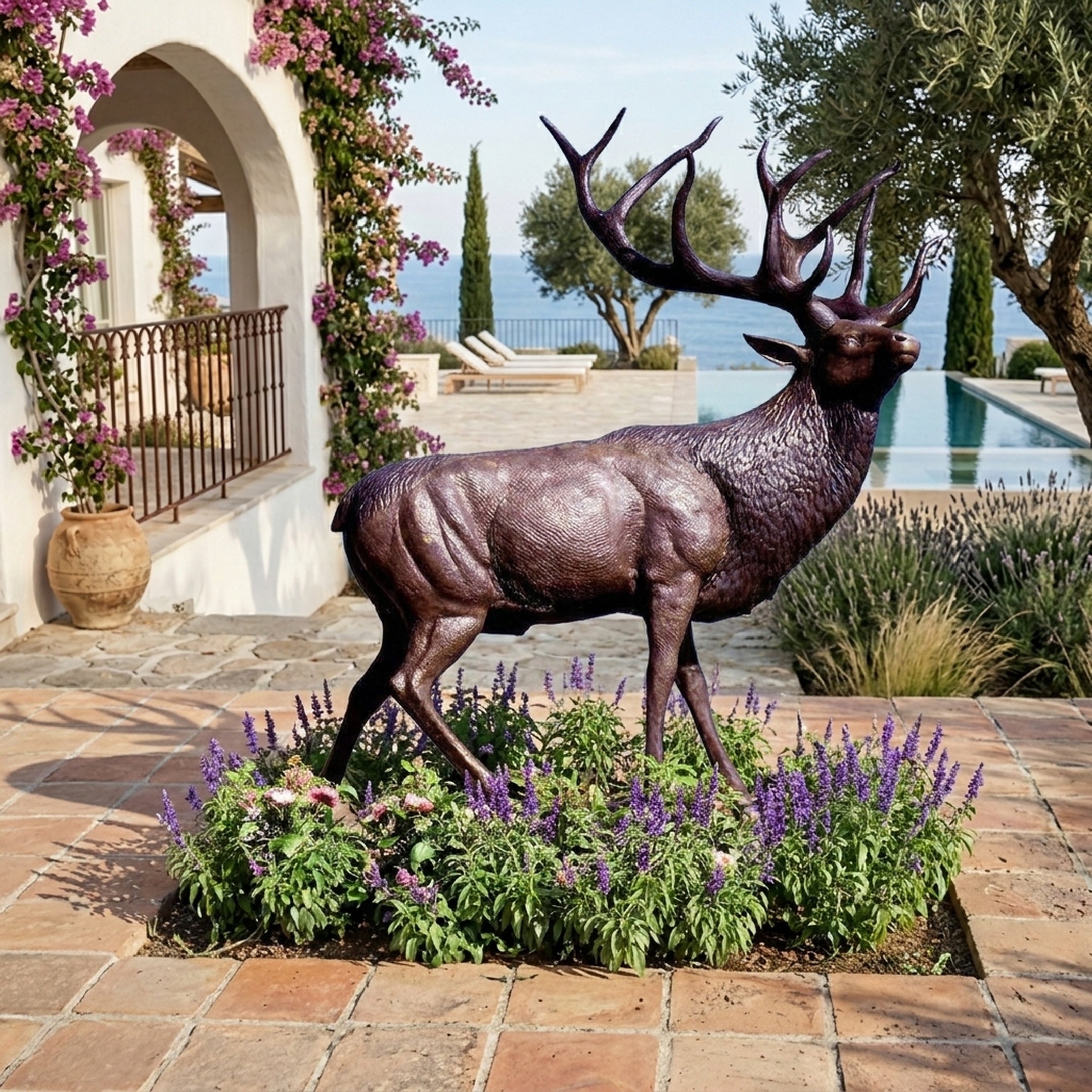 Life-Size Standing Bull Elk Bronze Sculpture by Giant Sculptures in dark-brown patina, set among lavender on a Mediterranean terrace with sea view and pool.