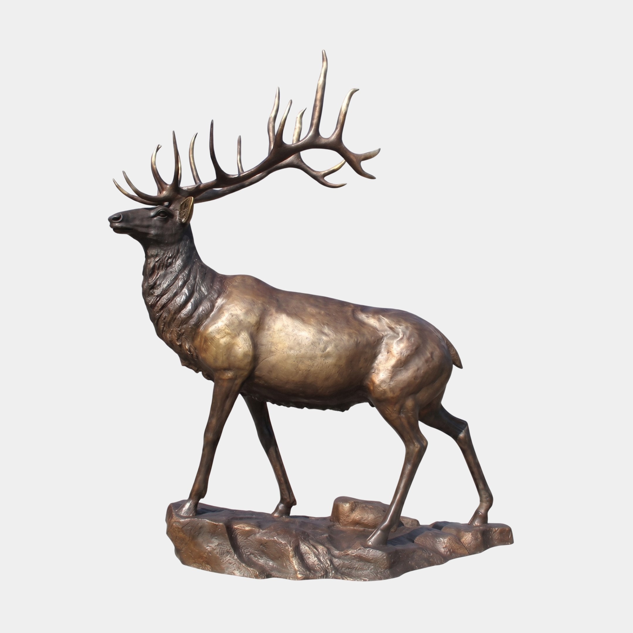 Life-Size Traditional Standing Elk Bronze Sculpture by Giant Sculptures, shown in side profile with raised head and wide multi-point antlers on a rocky bronze base.