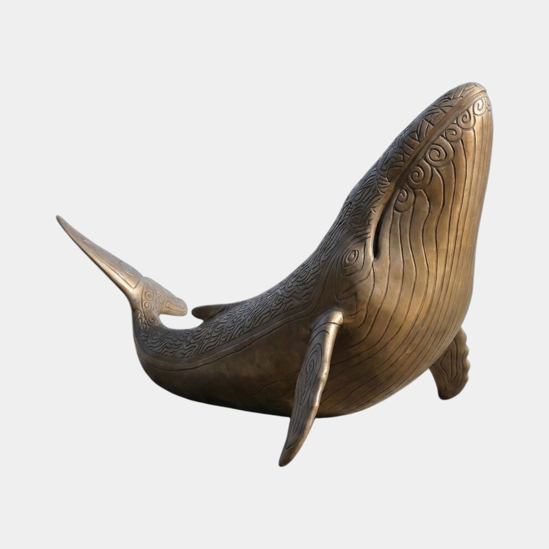 Monumental Breaching Humpback Whale Bronze Sculpture by Giant Sculptures, shown mid-breach with engraved spiral and wave motifs across the body, on a plain background.