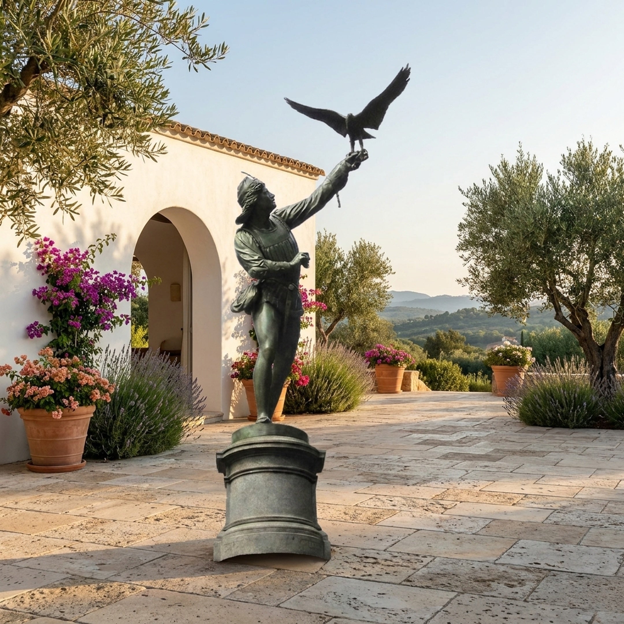Monumental Classical Falconer and Bird of Prey Bronze Sculpture by Giant Sculptures on a stone pedestal in a Mediterranean courtyard with olive trees.