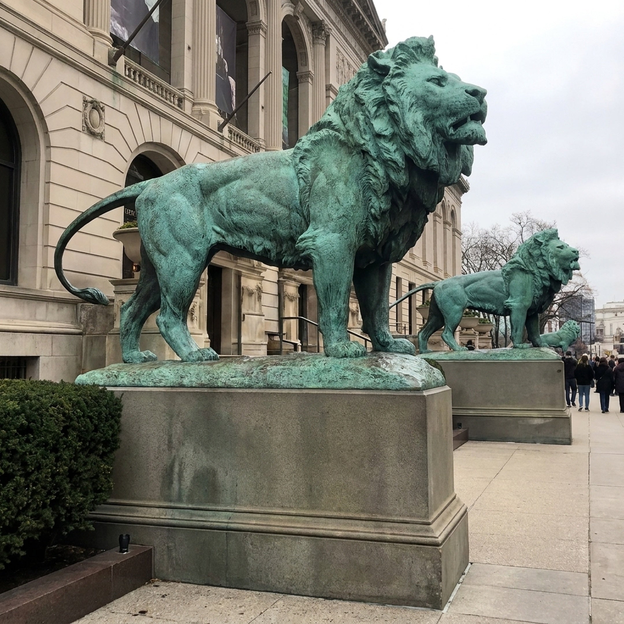 Monumental Classical Standing Lion Bronze Sculpture by Giant Sculptures, verdigris patina, shown in profile on stone pedestal flanking a classical building entrance.