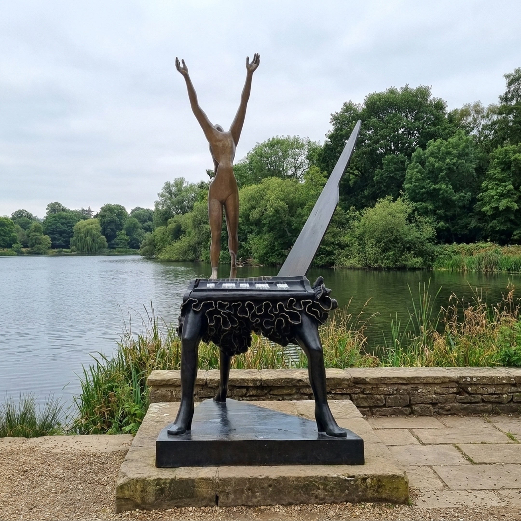 Rear view of Giant Sculptures' Monumental Contemporary Figure on Grand Piano Bronze Sculpture, bronze nude with arms raised on a black long-legged piano by a lake.