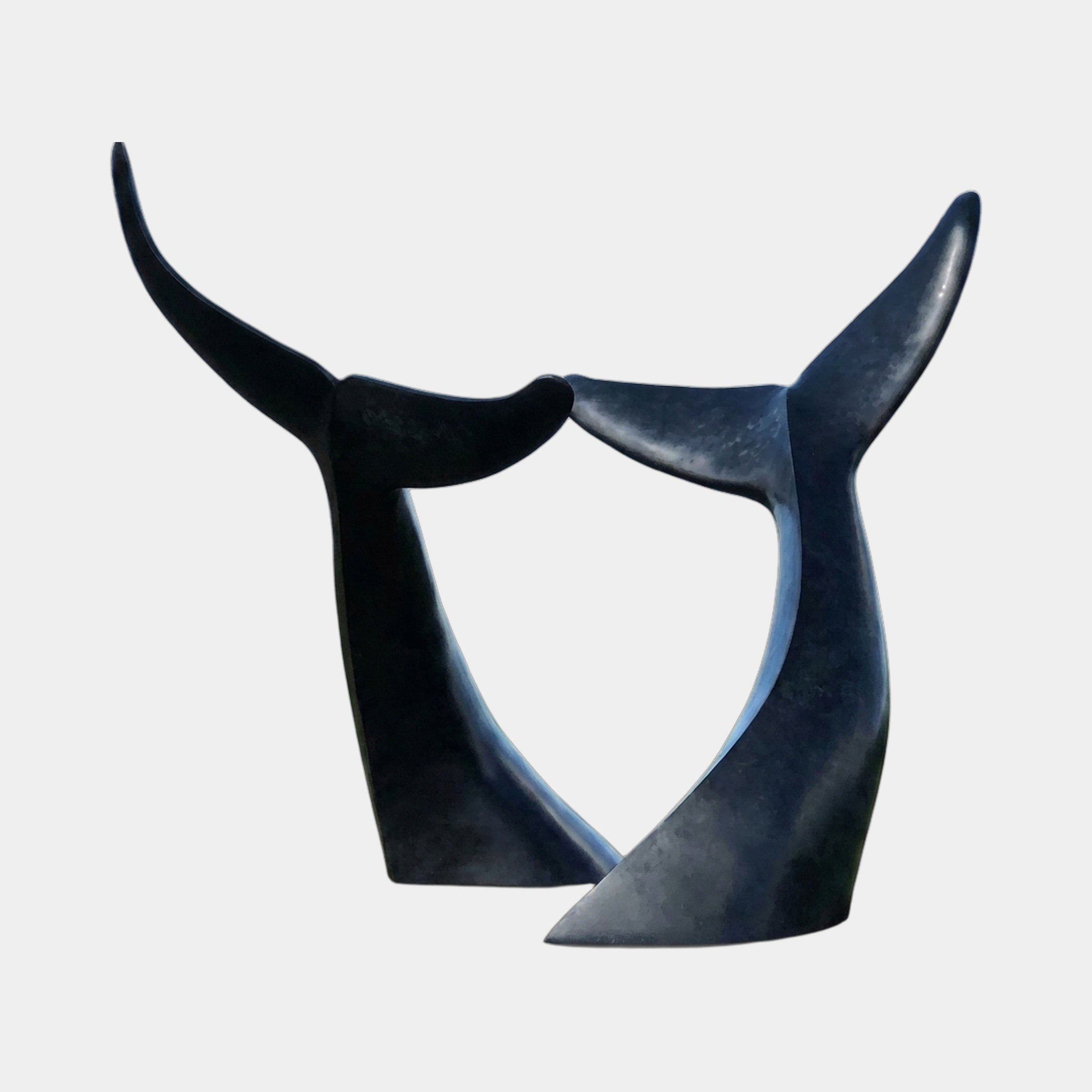 Monumental Interlocking Whale Tails Bronze Sculpture by Giant Sculptures, two black flukes curving up from a shared base, shown against a plain background.