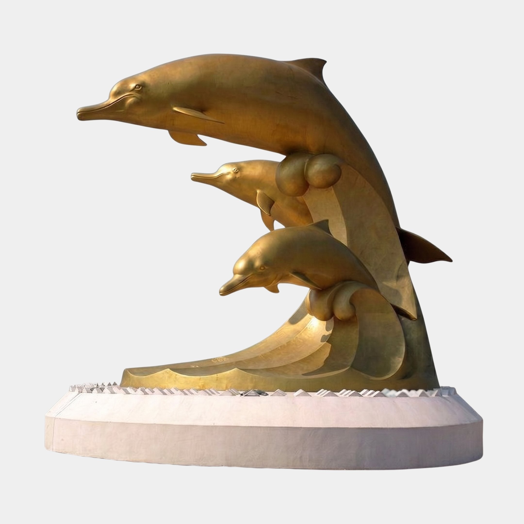 Monumental 900cm cast bronze sculpture by Giant Sculptures featuring three dolphins with polished gold patina leaping from a stylised wave on a white plinth.