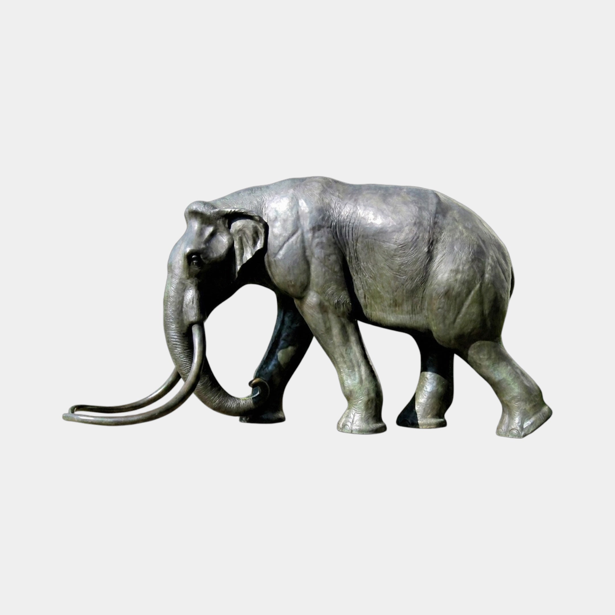 Monumental Life-Size Walking Elephant Bronze Sculpture by Giant Sculptures, side view with long sweeping tusks and dark patina, shown on a plain background.