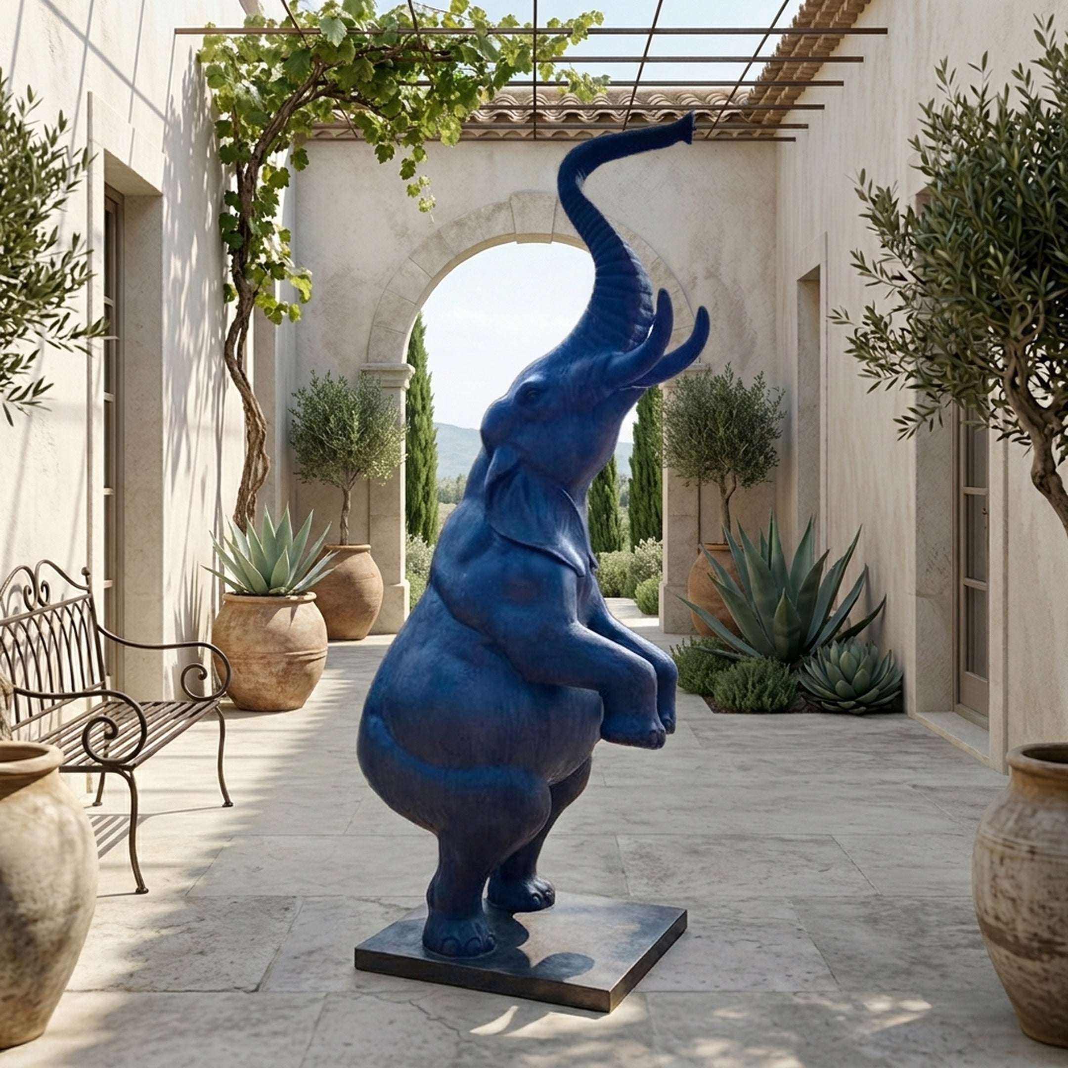 Monumental Rearing Elephant Bronze Sculpture by Giant Sculptures in deep blue finish, trunk raised skyward, displayed on a Mediterranean stone courtyard.