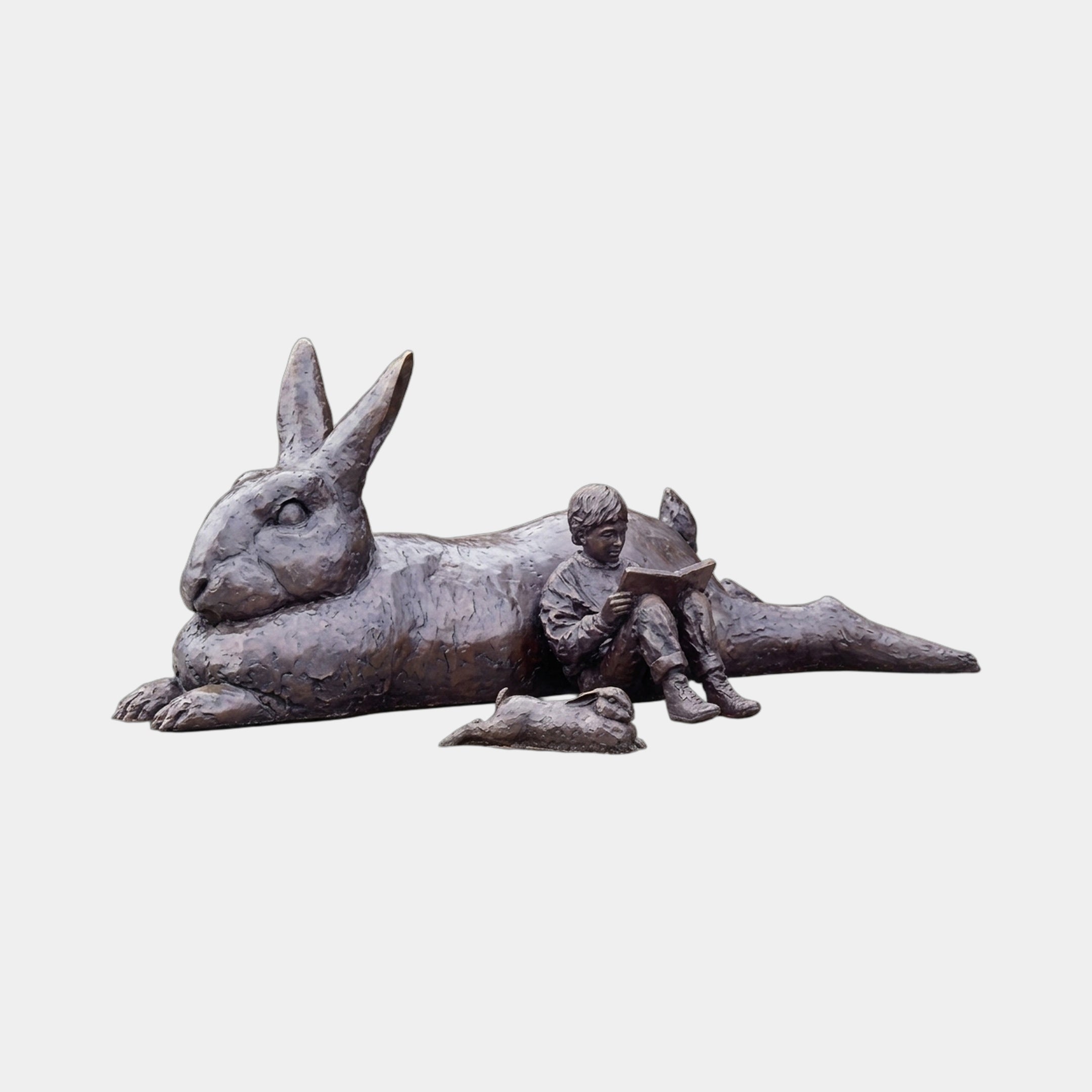 Monumental Reclining Rabbit and Child Reading Bronze Sculpture by Giant Sculptures, 180cm, dark patina, with a small rabbit and child reading at its side.