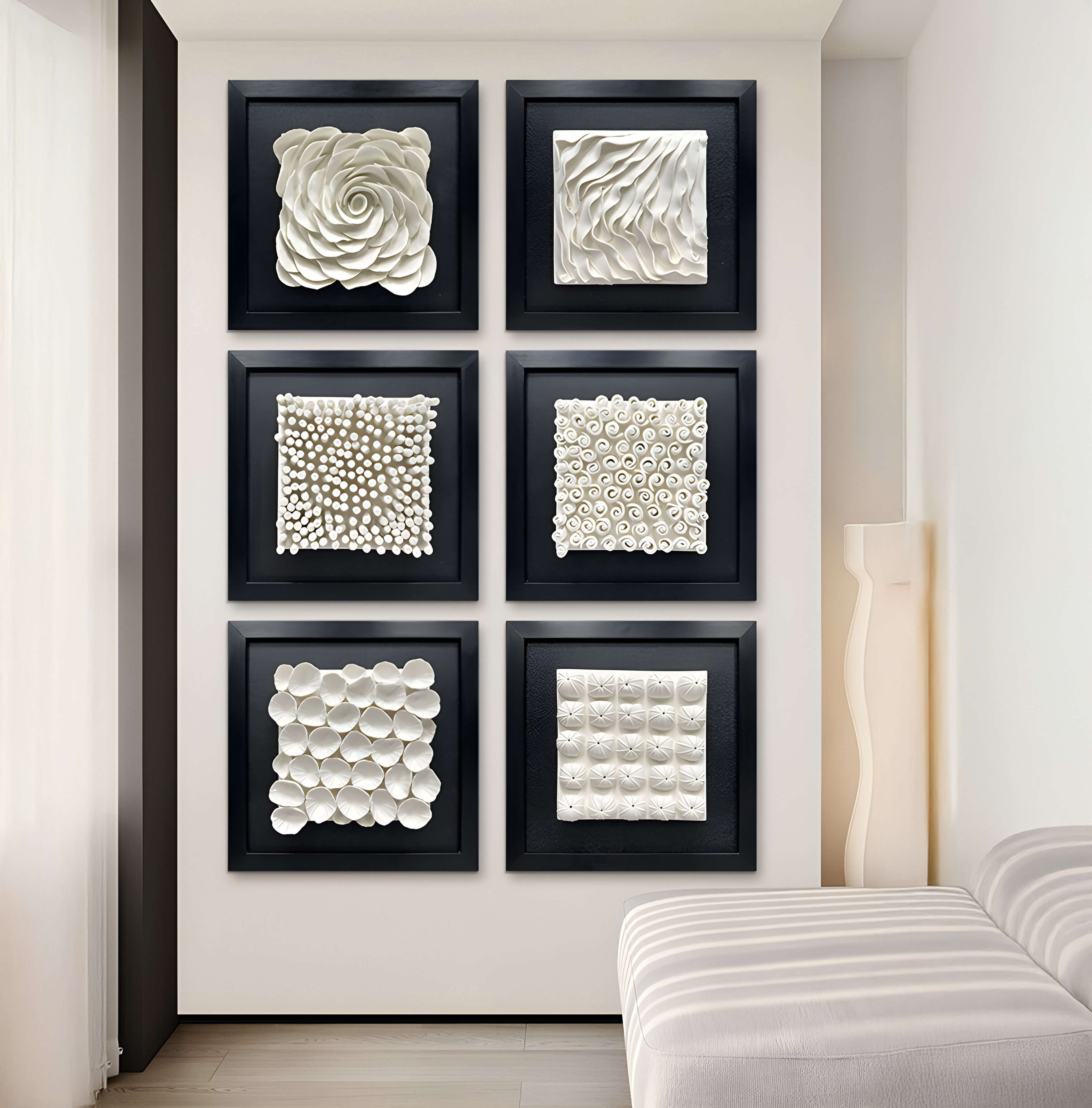 Six Harmonia 3D Spiral Wall Sculptures by Giant Sculptures, framed in black and featuring ceramic spirals and petal patterns, create a modern aesthetic. Arranged in two columns of three, they are complemented by a white bench as soft light filters through a sheer curtain.
