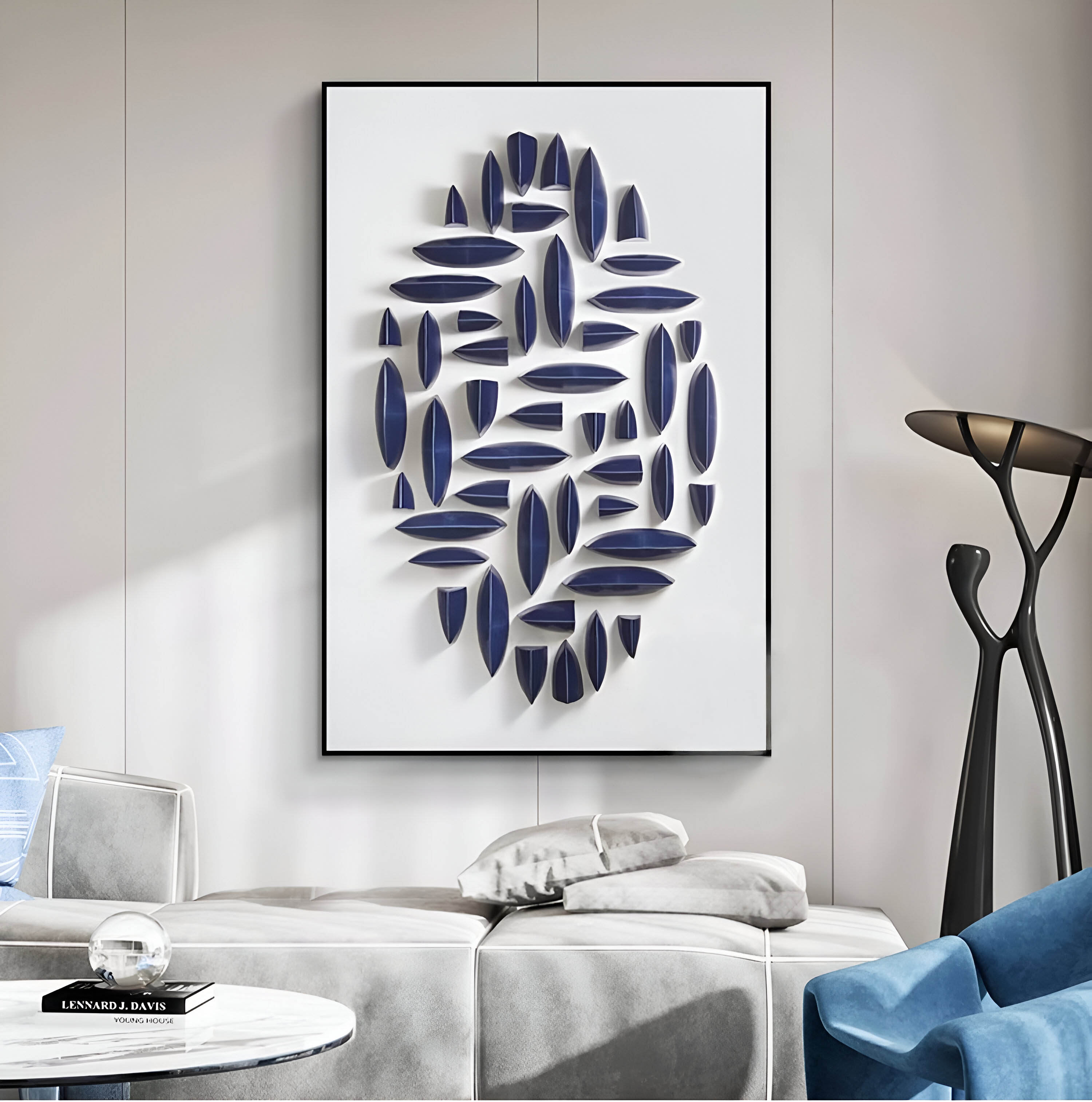 A modern living room features the Elysian 3D Ceramic Wall Art by Giant Sculptures, displaying a vertical blue geometric design on a white background. A sleek floor lamp complements a gray sofa with plush pillows, and a book-stacked table completes the contemporary vibe.
